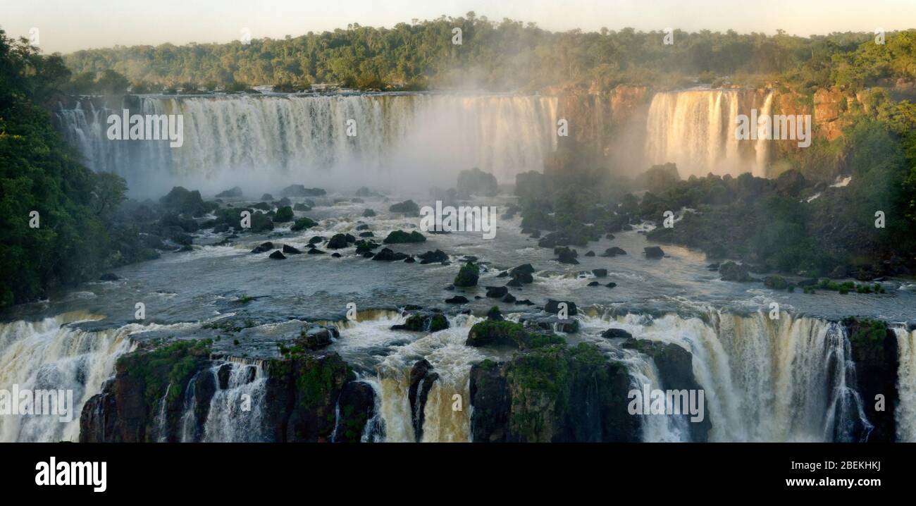 Acqua che si riversa sulle cascate di Iguacu, Brasile, sotto la luce del sole Foto Stock