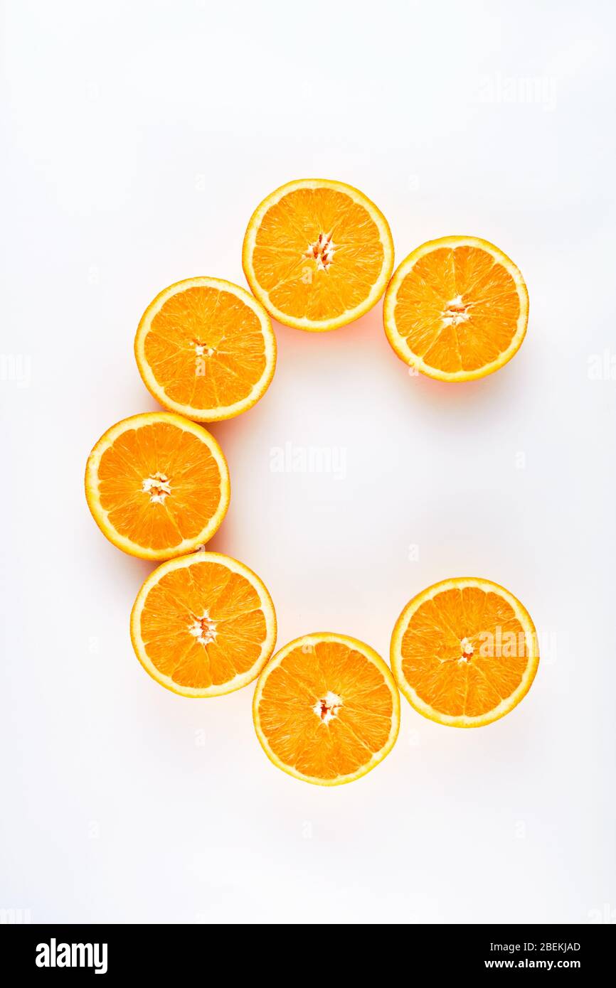 Fette di arancio dimezzate disegnate come lettera c che rappresenta la vitamina c su sfondo bianco. Alimentazione sana per il sistema immunitario. Foto Stock