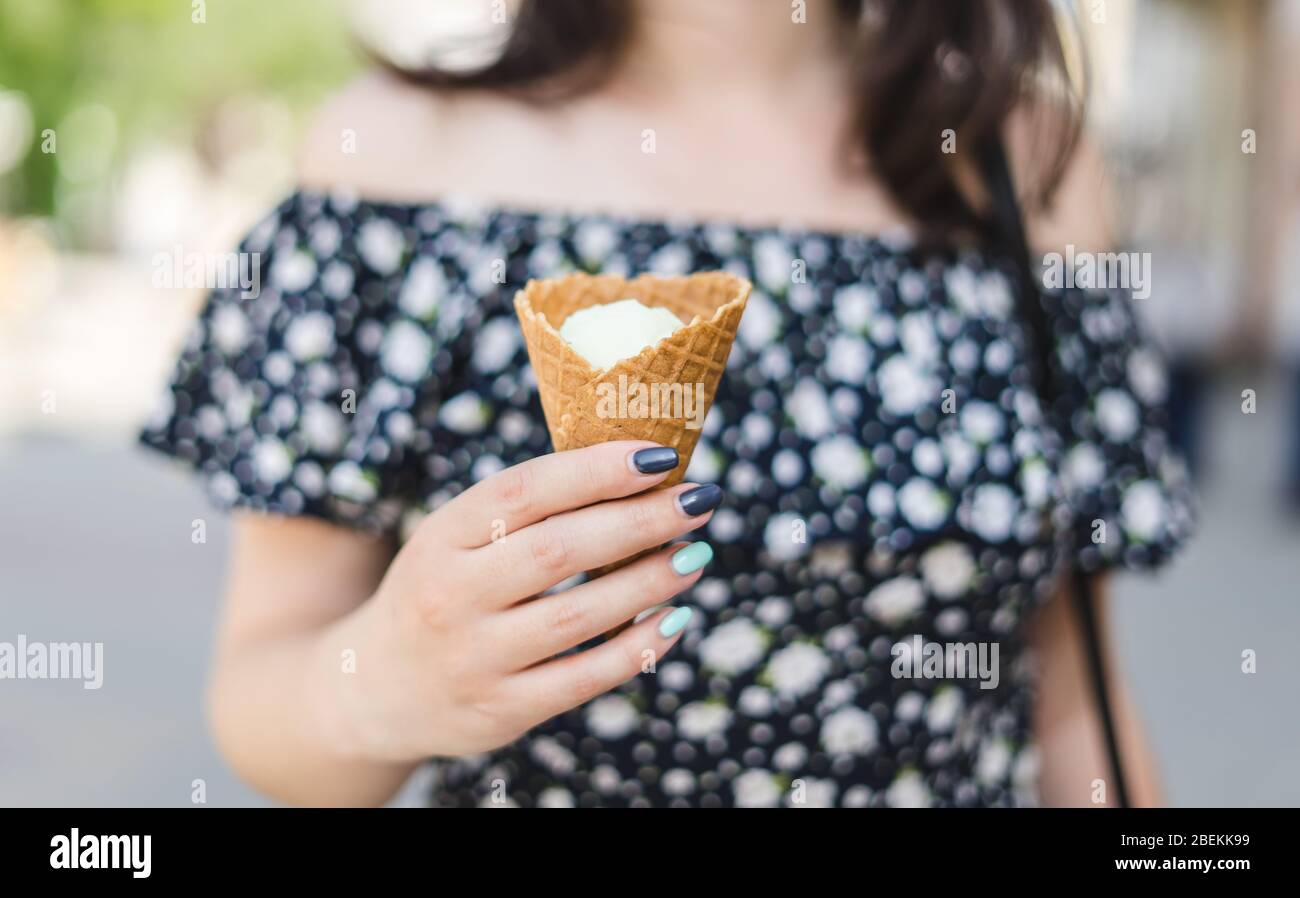 Donna joung tiene gelato alla vaniglia nel cono. Gelato alla vaniglia in un cono di waffle Foto Stock