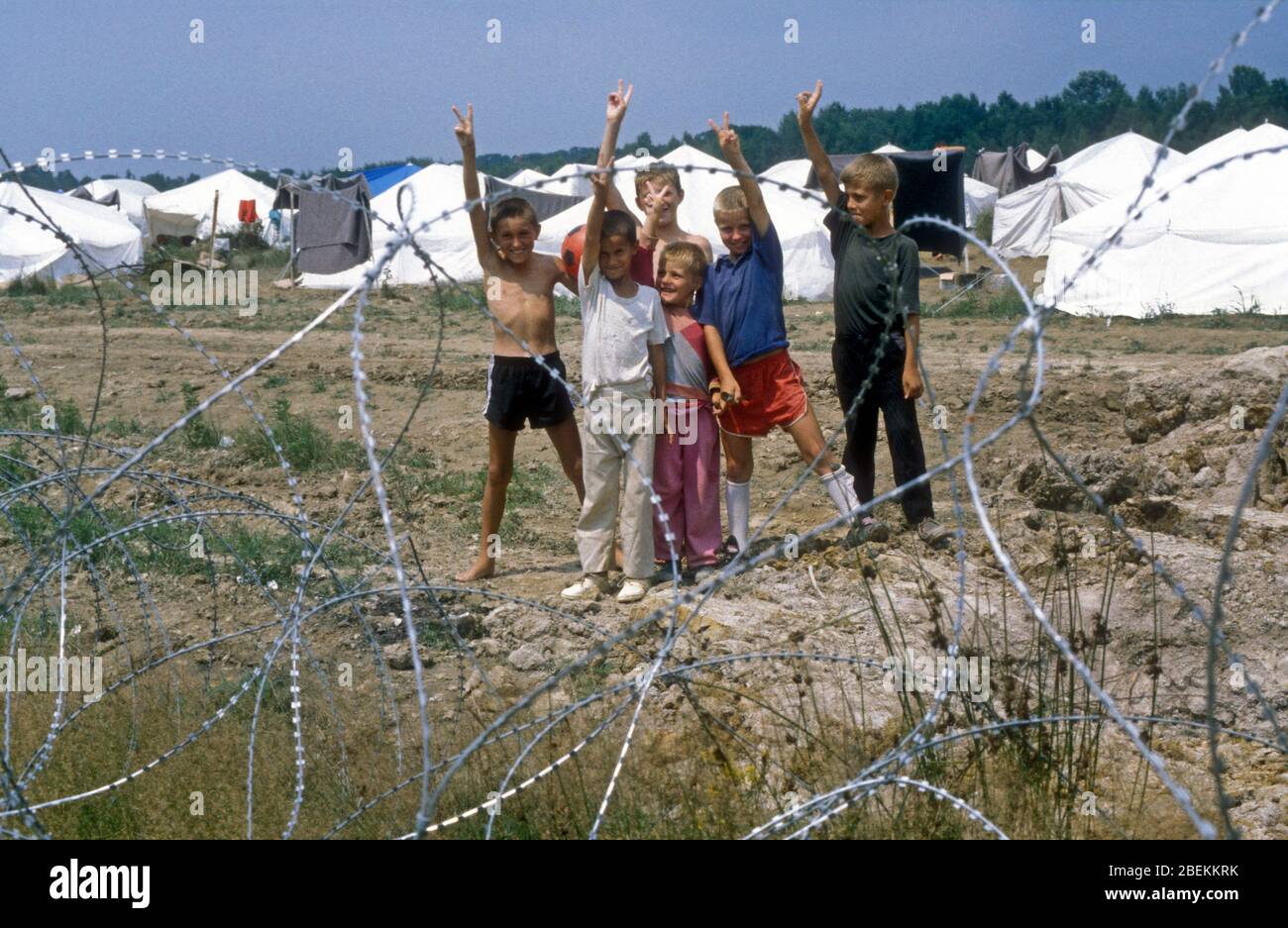 1995 Tuzla, Bosnia - i bambini rifugiati senza tetto danno il loro saluto alla vittoria nel campo aereo di Tuzla, il campo profughi temporaneo delle Nazioni Unite per i musulmani bosniaci in fuga dal massacro di Srebrenica durante la guerra bosniaca Foto Stock