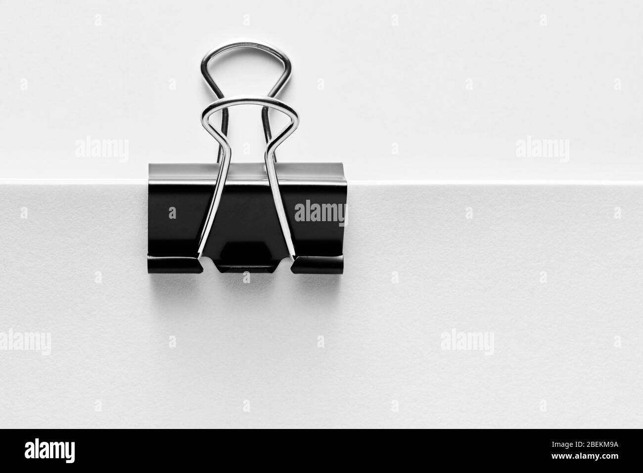 Graffetta nera attaccata all'angolo di una carta bianca vuota. Vista ravvicinata. Foto Stock