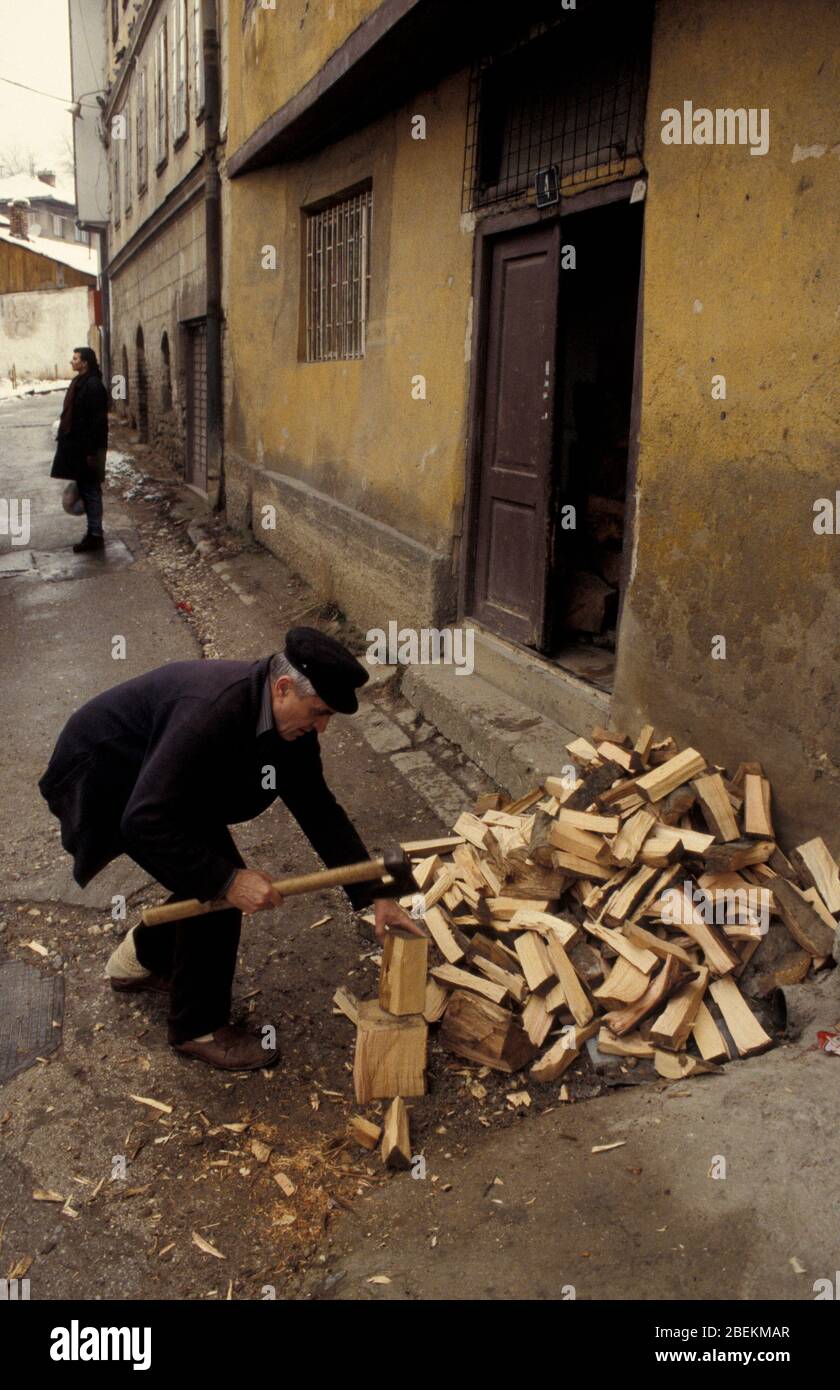 Sarajevo 1995 - uomo tagliando legna da ardere per rimanere caldo durante l'assedio in inverno, Bosnia-Erzegovina Foto Stock