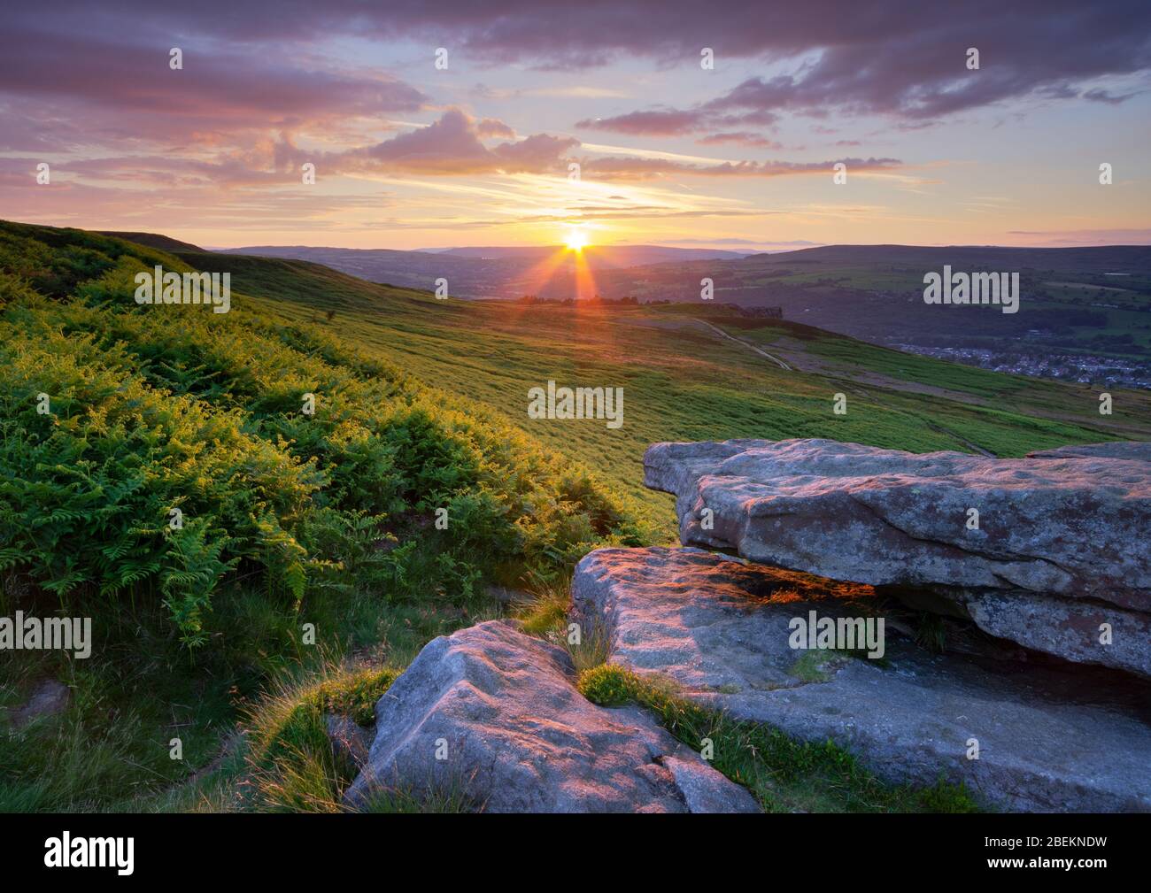 Il sole tramonta l'ultima luce sul verde bracken che copre Ilkley Moor, visto da Pancake Rock, in alto sopra la città termale di Ilkley. Foto Stock