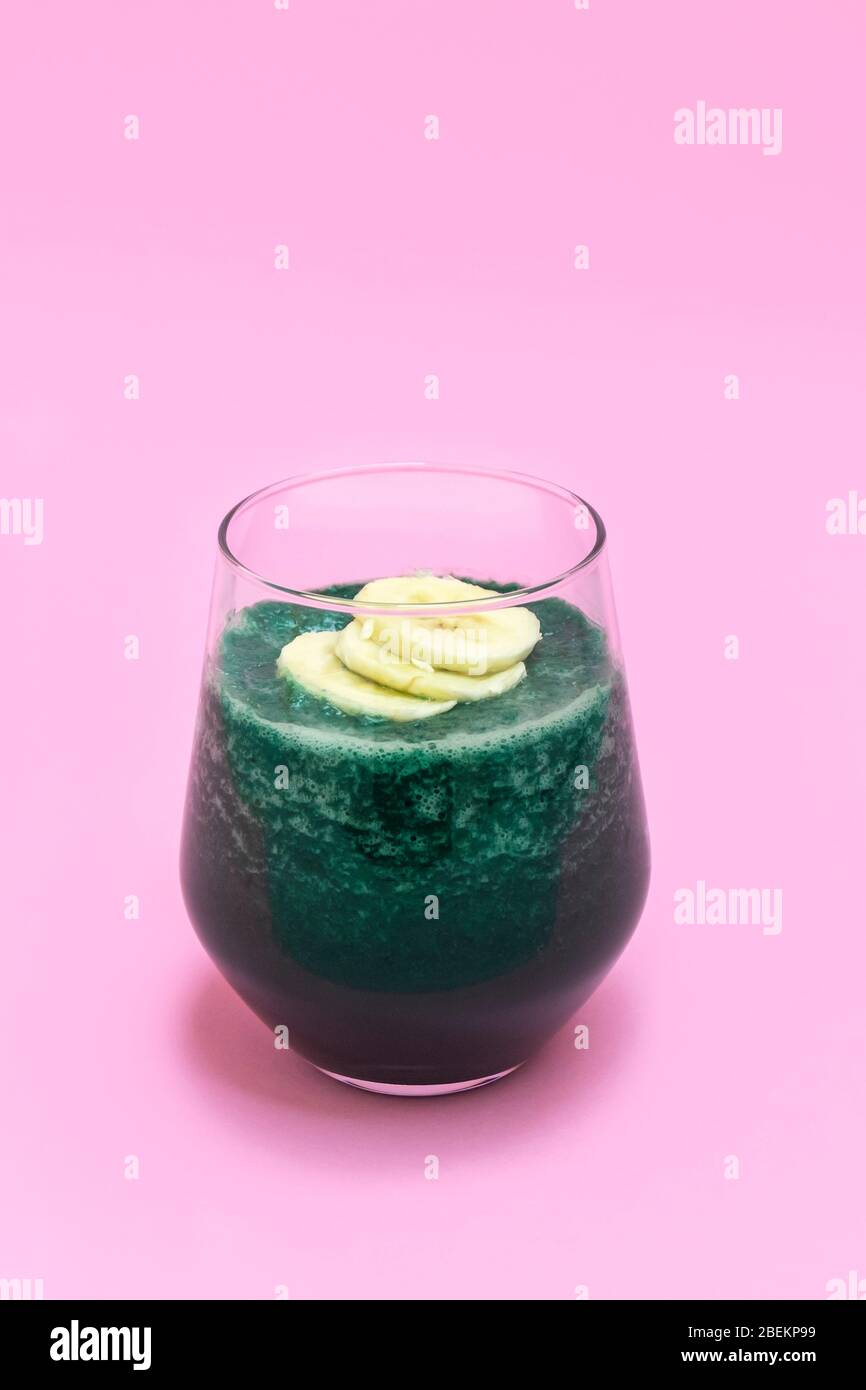 Coppa di vetro di disintossicazione spirulina su sfondo rosa pastello Foto Stock