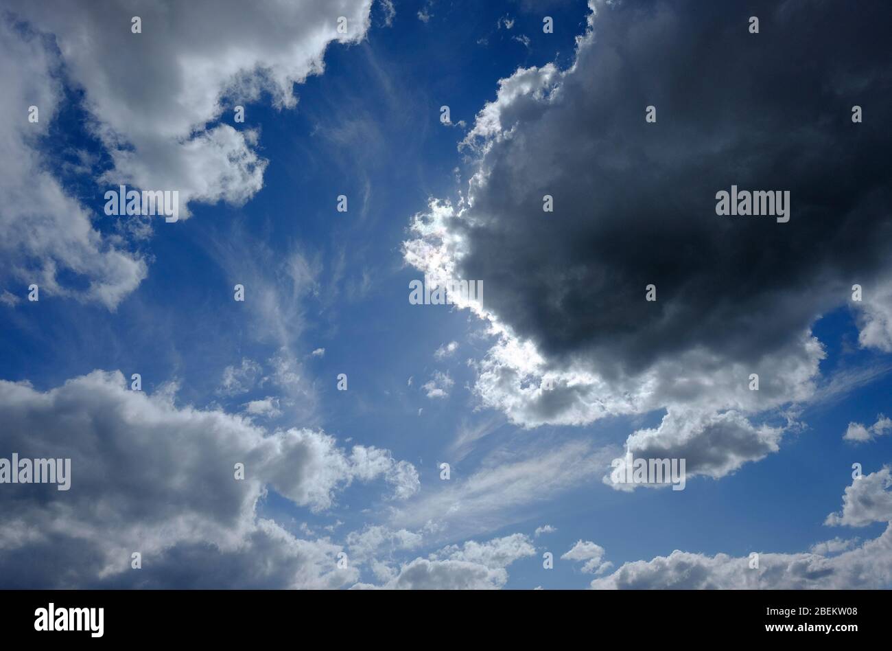 sole dietro nuvole scure su cielo blu Foto Stock