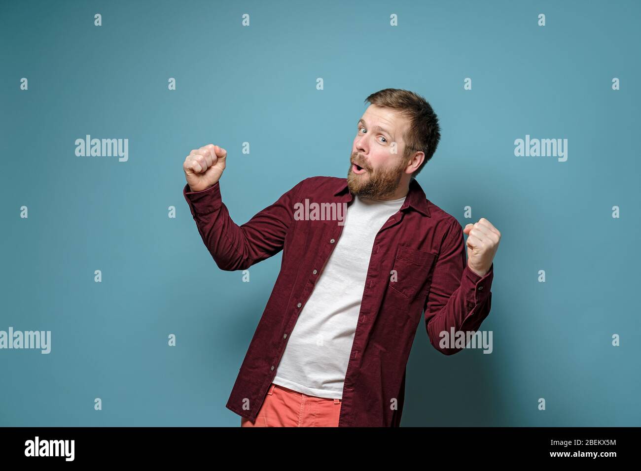 Attraente, allegro uomo è soddisfatto del suo successo, fa un gesto con le mani e guarda nella fotocamera con occhi gioiosi. Foto Stock