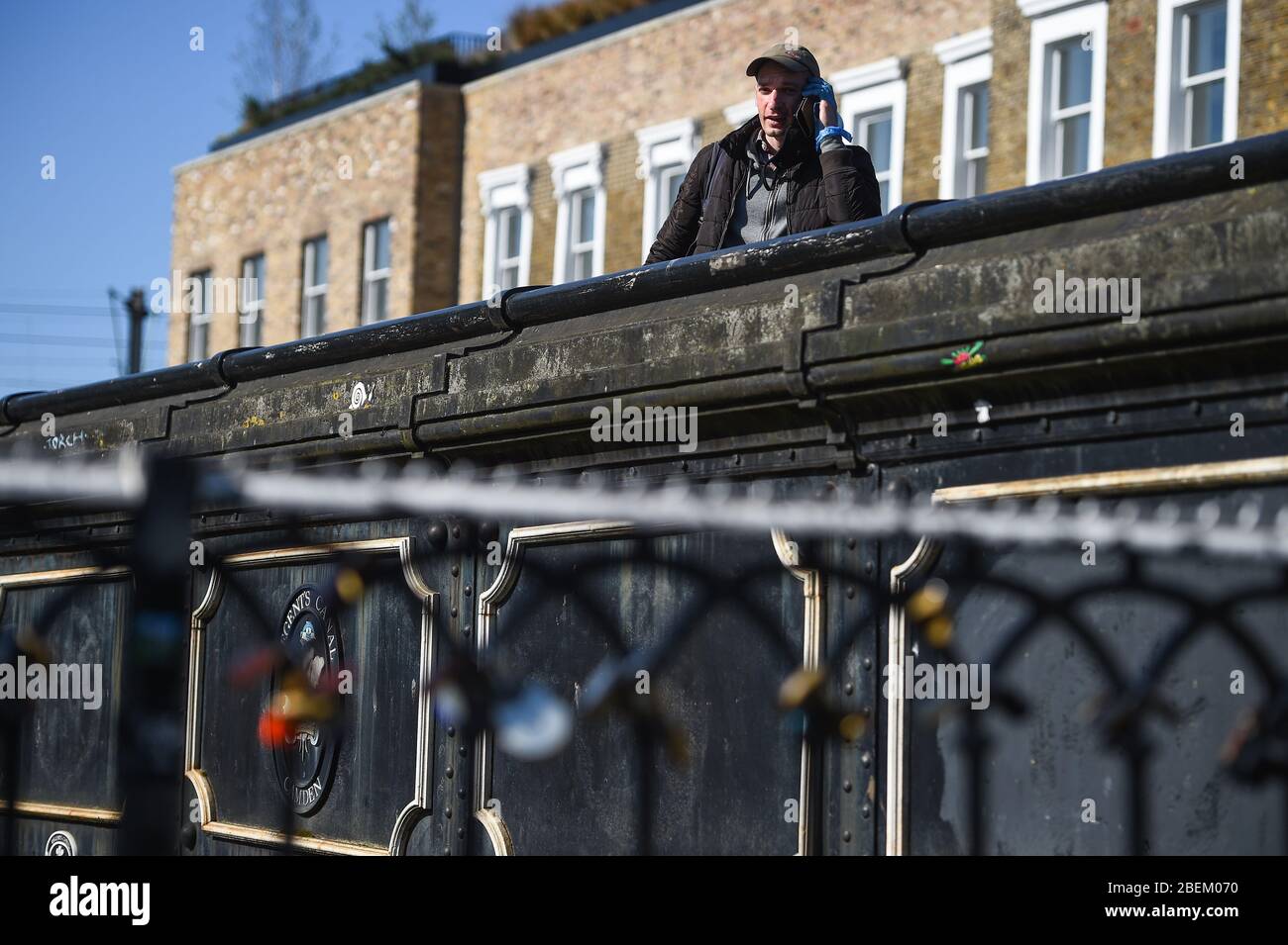 Un uomo che indossa i guanti attraversa un ponte su Camden Lock, Londra, mentre il Regno Unito continua a bloccarsi per contribuire a frenare la diffusione del coronavirus. Foto Stock
