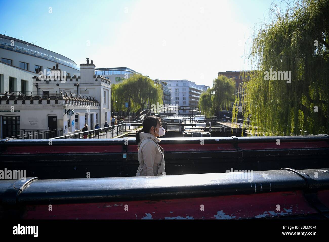 Una donna che indossa una maschera attraversa un ponte su Camden Lock, Londra, mentre il Regno Unito continua a bloccarsi per contribuire a frenare la diffusione del coronavirus. Foto Stock