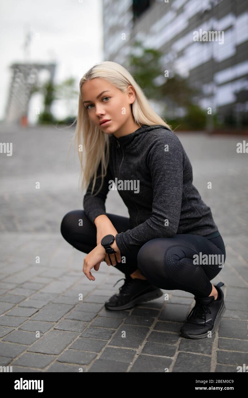 Una donna Runner sportiva e dal buon look con smartwatch in un ambiente urbano moderno Foto Stock