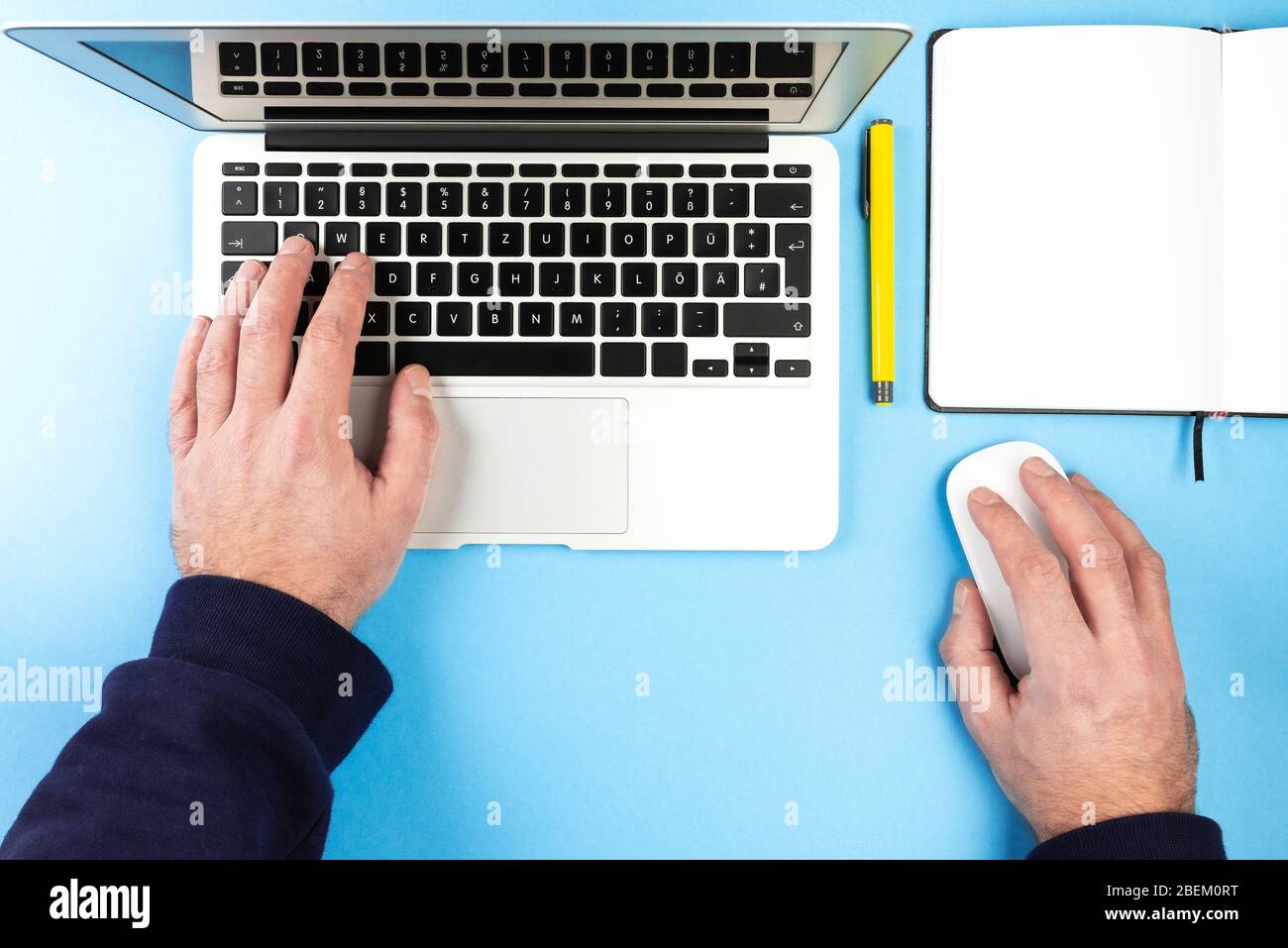 vista dall'alto dell'uomo che usa un computer portatile e un mouse sulla scrivania con blocco note e penna Foto Stock