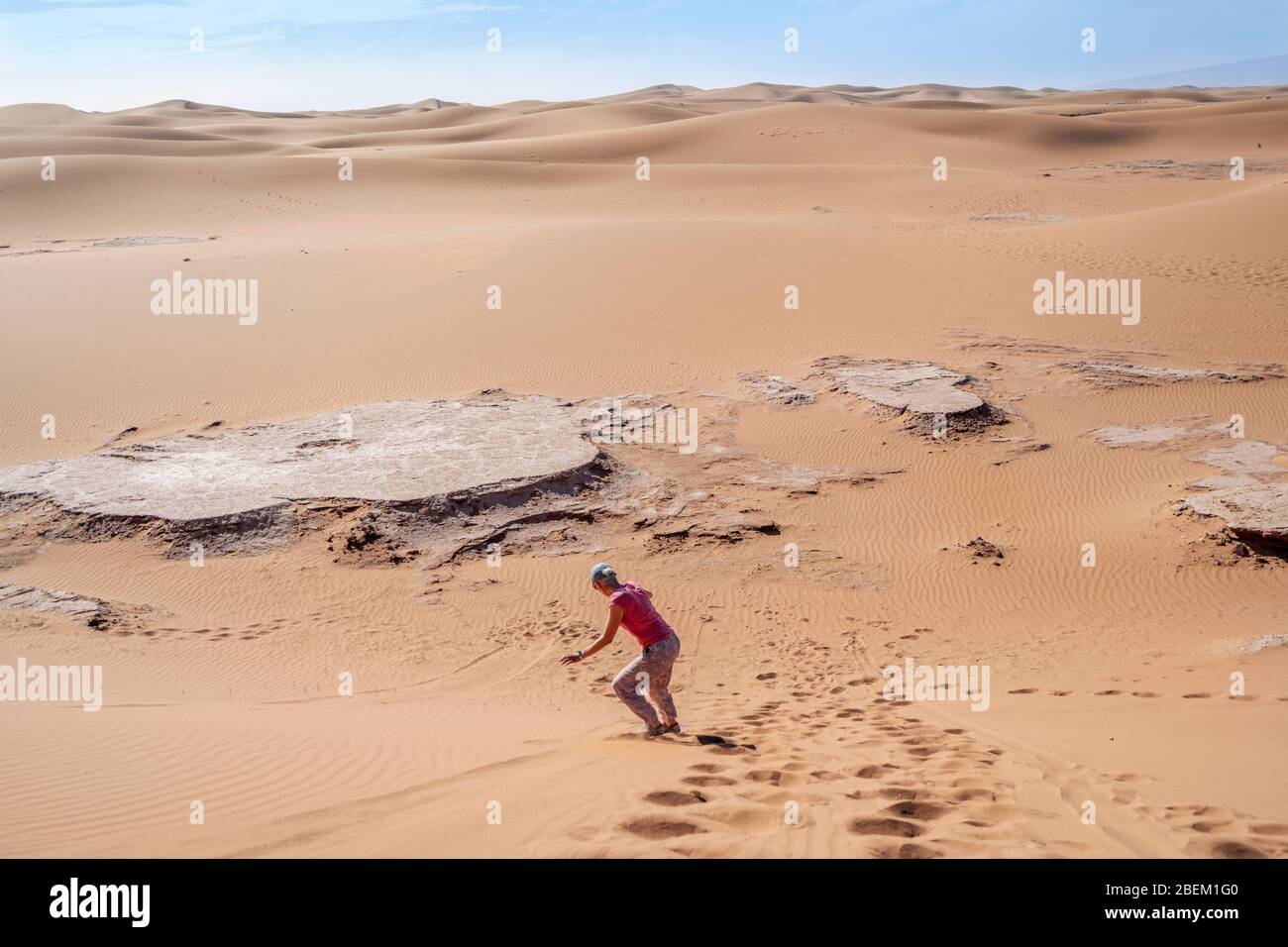 Donna sandboarding sul deserto del Sahara lungo la duna, Marocco, Africa Foto Stock