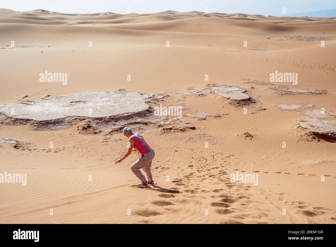 Donna sandboarding sul deserto del Sahara lungo la duna, Marocco, Africa Foto Stock