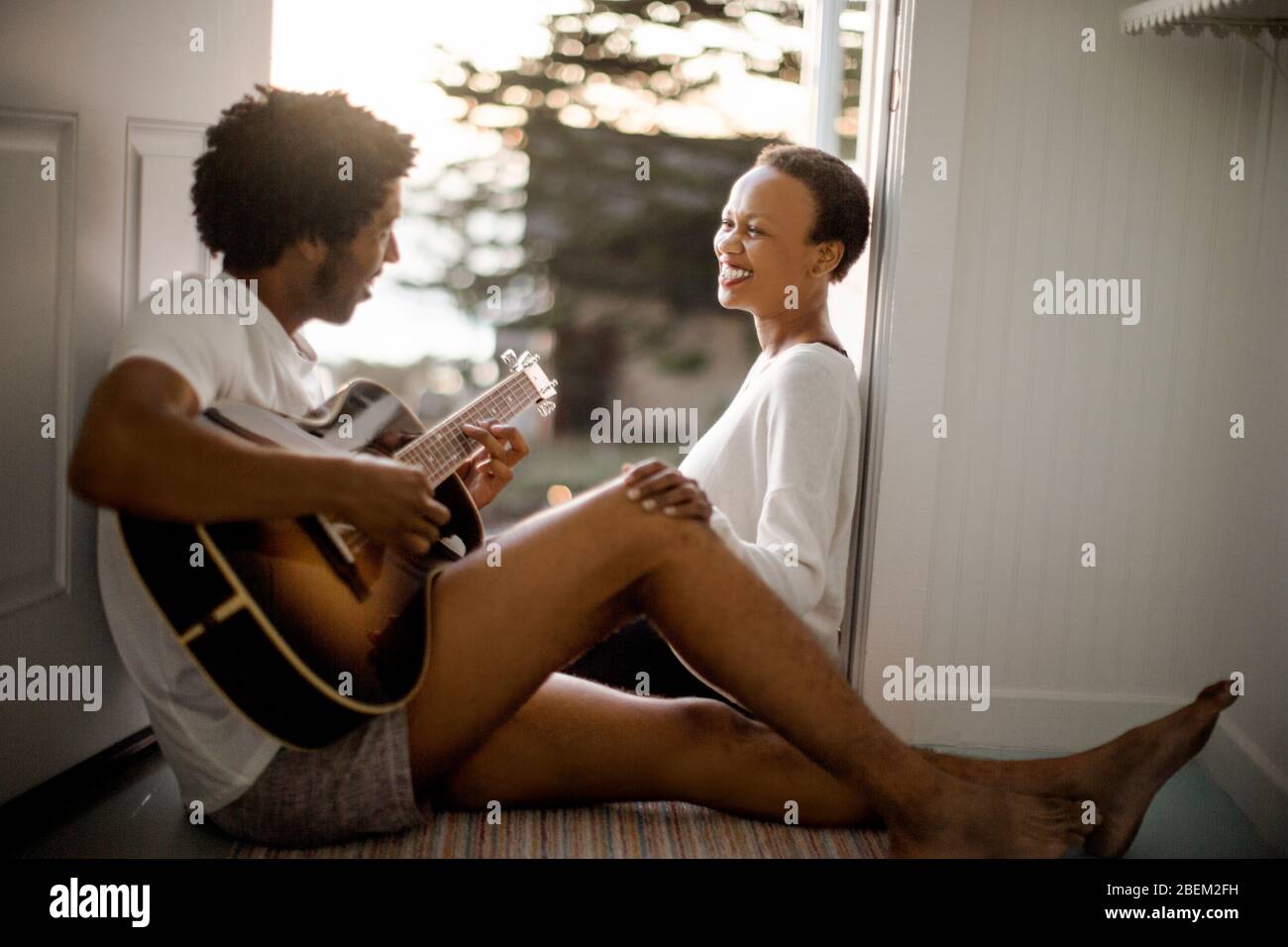Giovane uomo che suona la chitarra per la sua ragazza sorridente Foto Stock