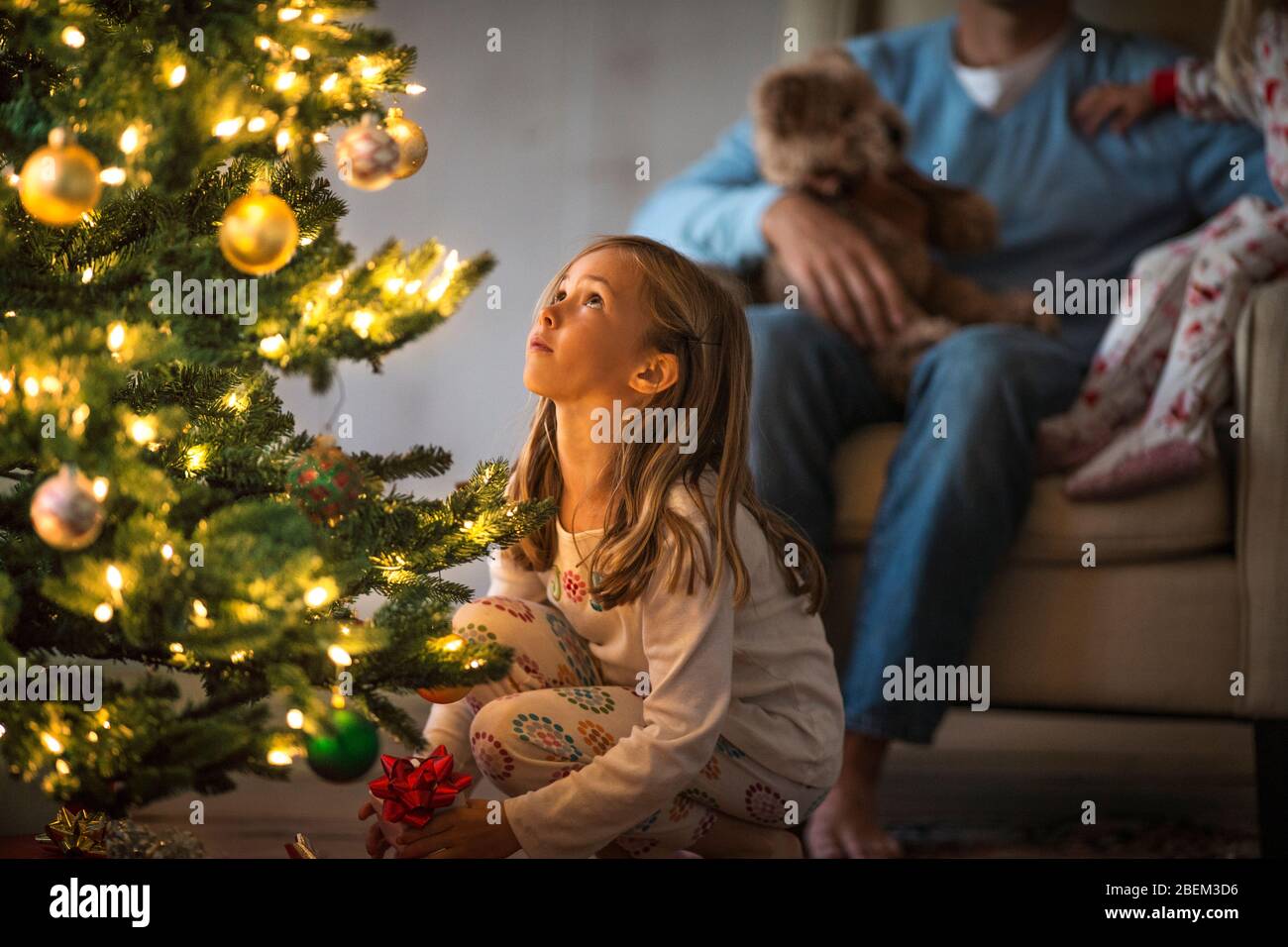 Giovane ragazza che guarda le decorazioni su un albero di Natale illuminato Foto Stock