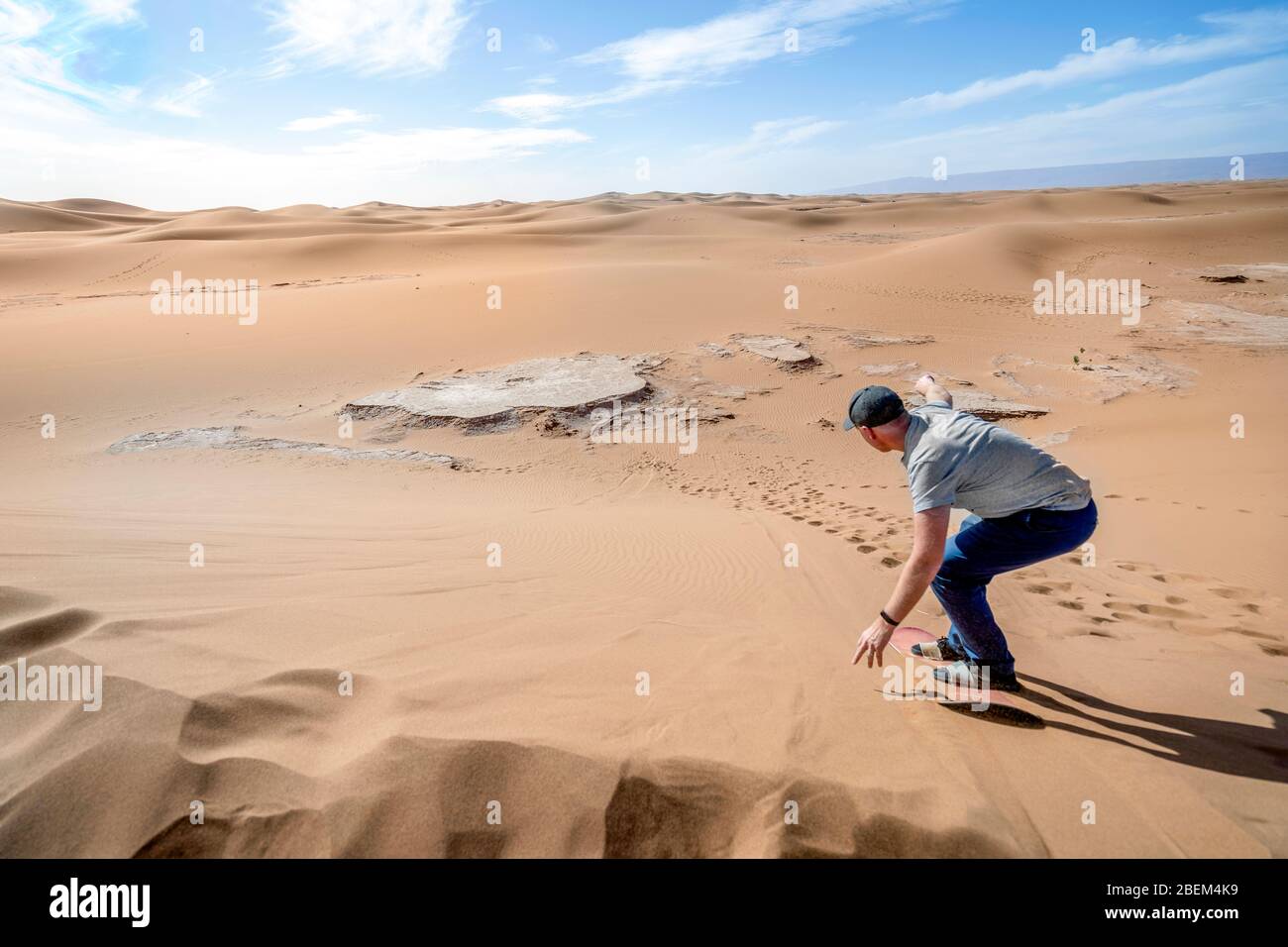 Uomo sandboarding sul deserto del Sahara lungo la duna, Marocco, Africa Foto Stock