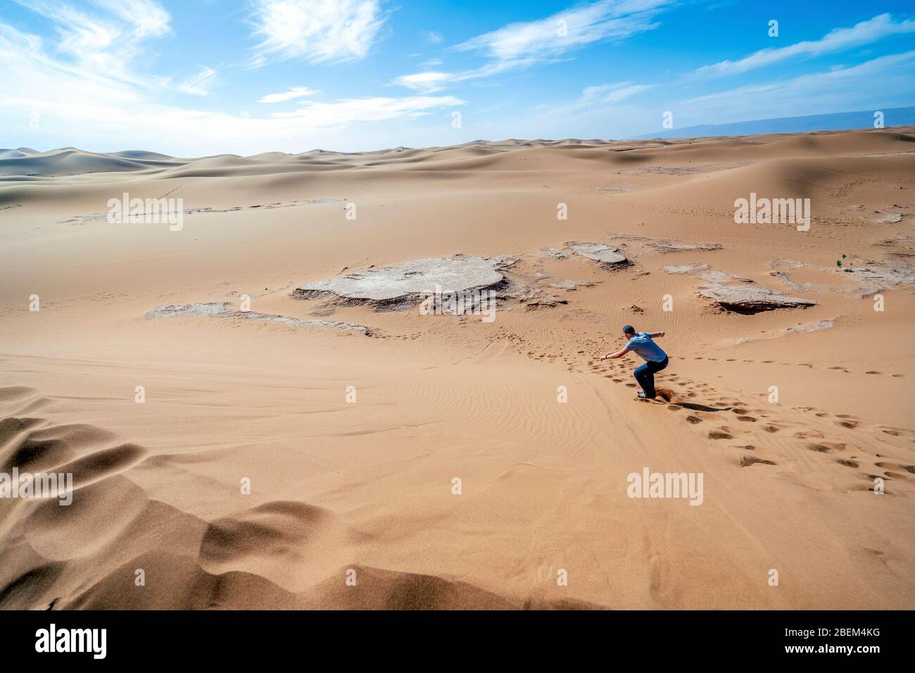 Uomo sandboarding sul deserto del Sahara lungo la duna, Marocco, Africa Foto Stock