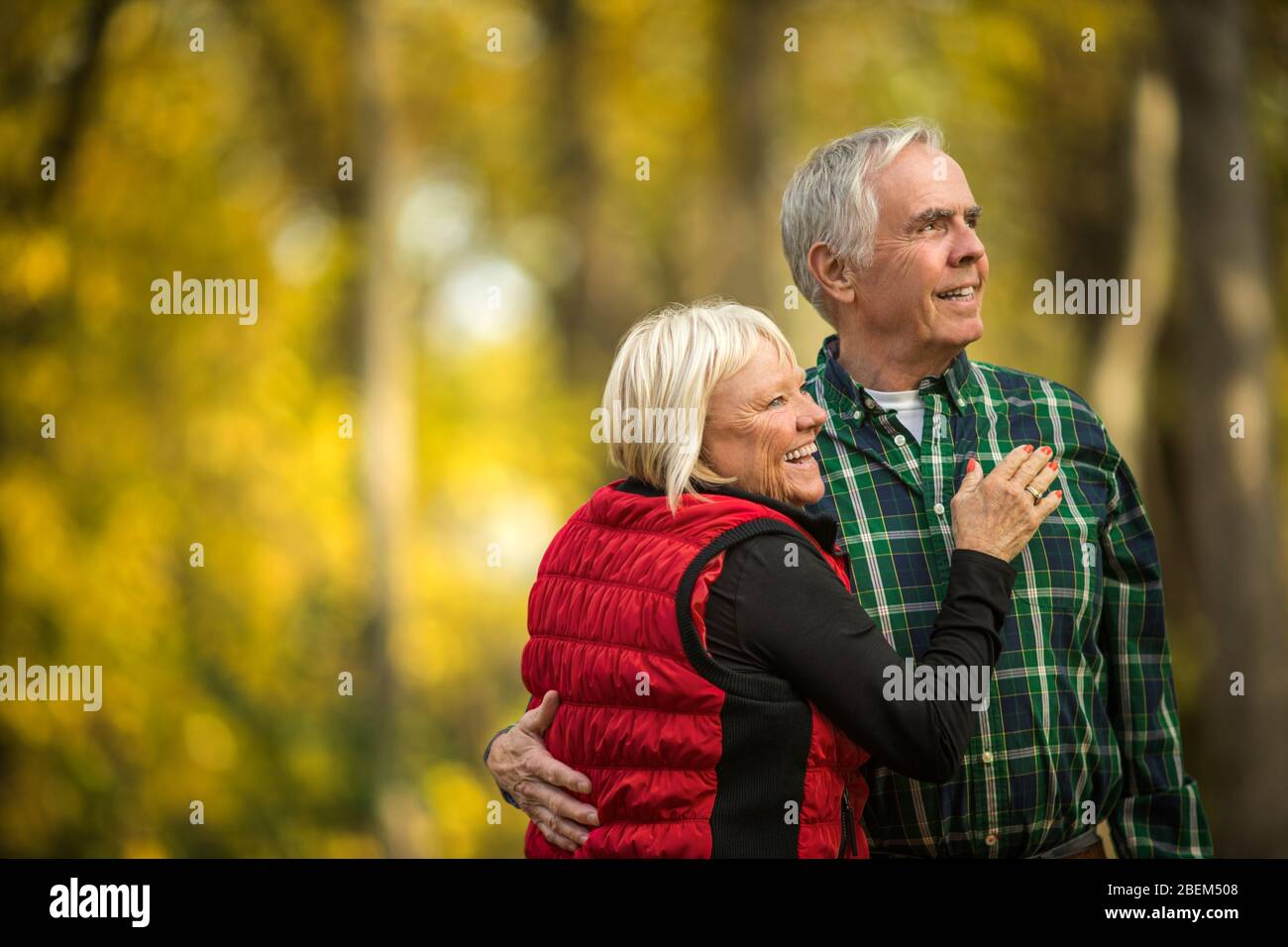 Felice coppia senior abbracciando mentre si guarda fuori nella foresta Foto Stock