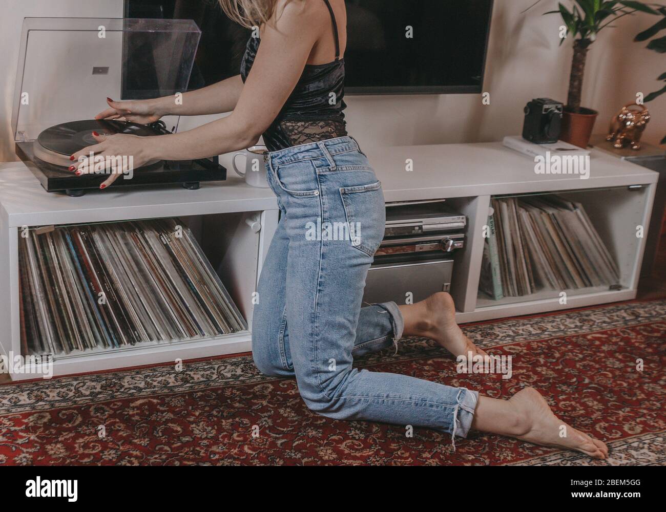 Giovane donna che mette un disco vinilico sopra. Foto Stock
