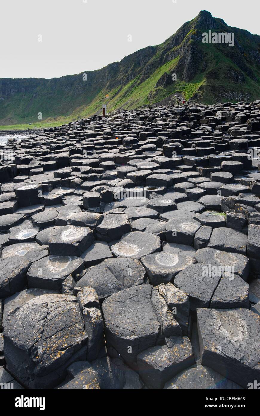 Un sentiero di pietre con una montagna sullo sfondo al Giant's Causeway, Antrim Coast, Irlanda del Nord, Regno Unito Foto Stock
