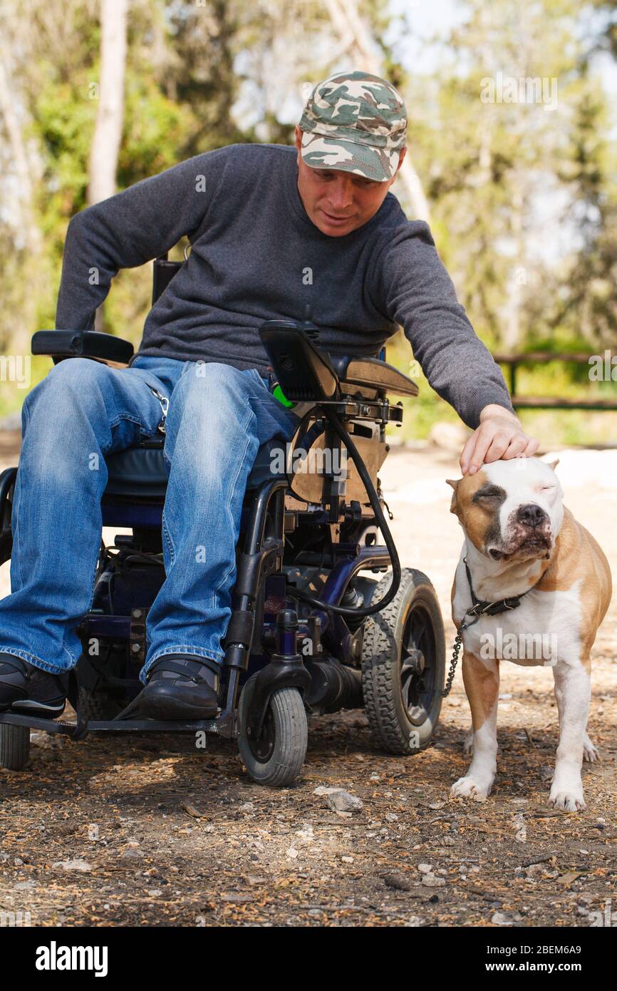 Giovane in carrozzina con il suo fedele cane a piedi nel parco. Foto Stock