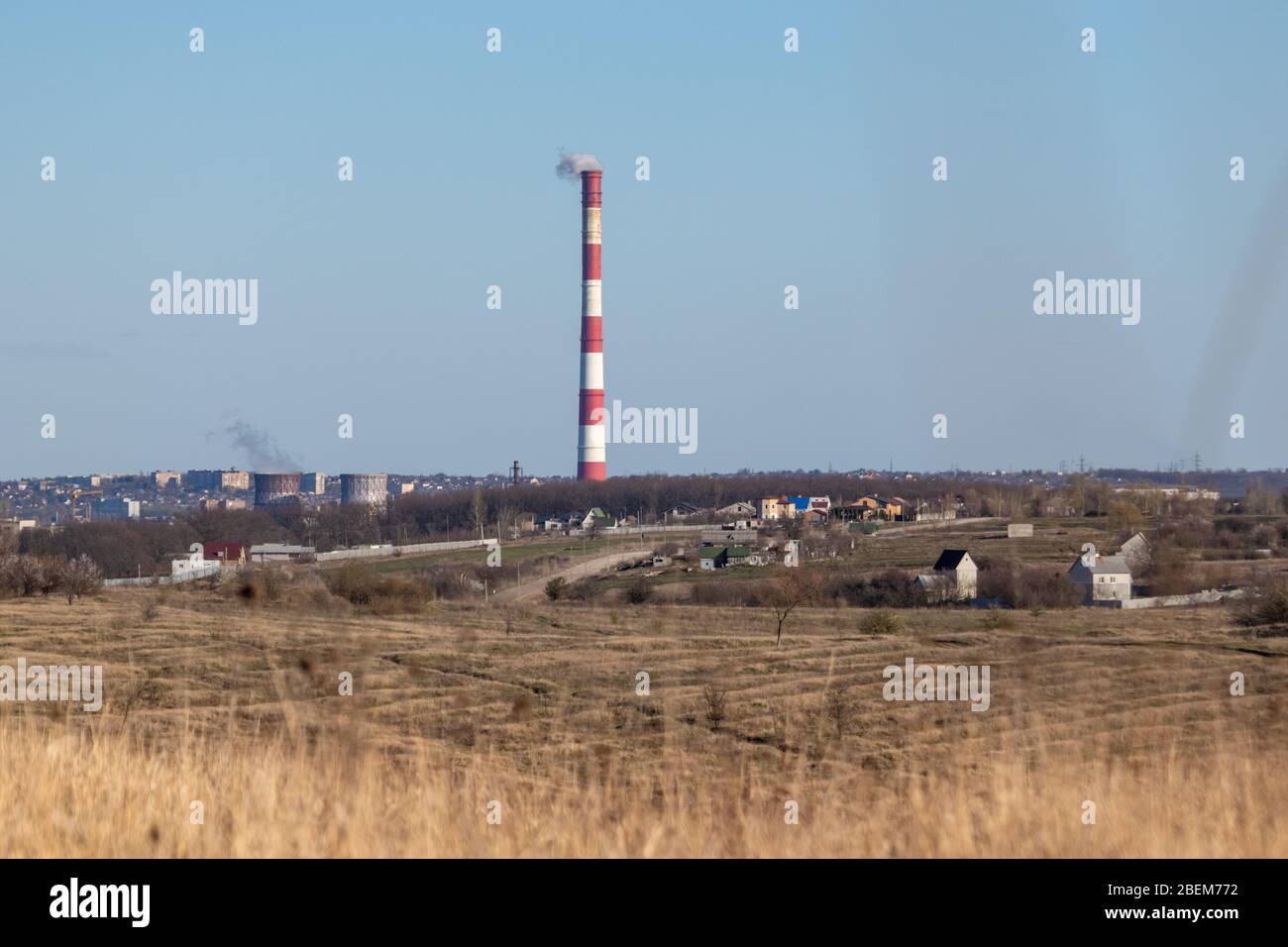 Tubo per centrale elettrica a calore energetico con strisce bianche rosse. Europa, campagna Ucraina, cielo limpido paesaggio con inquinamento atmosferico fumo torre. Foto Stock