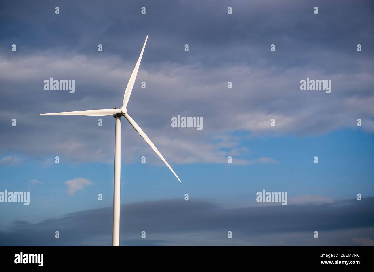 Turbina eolica singola contro un cielo nuvoloso Foto Stock