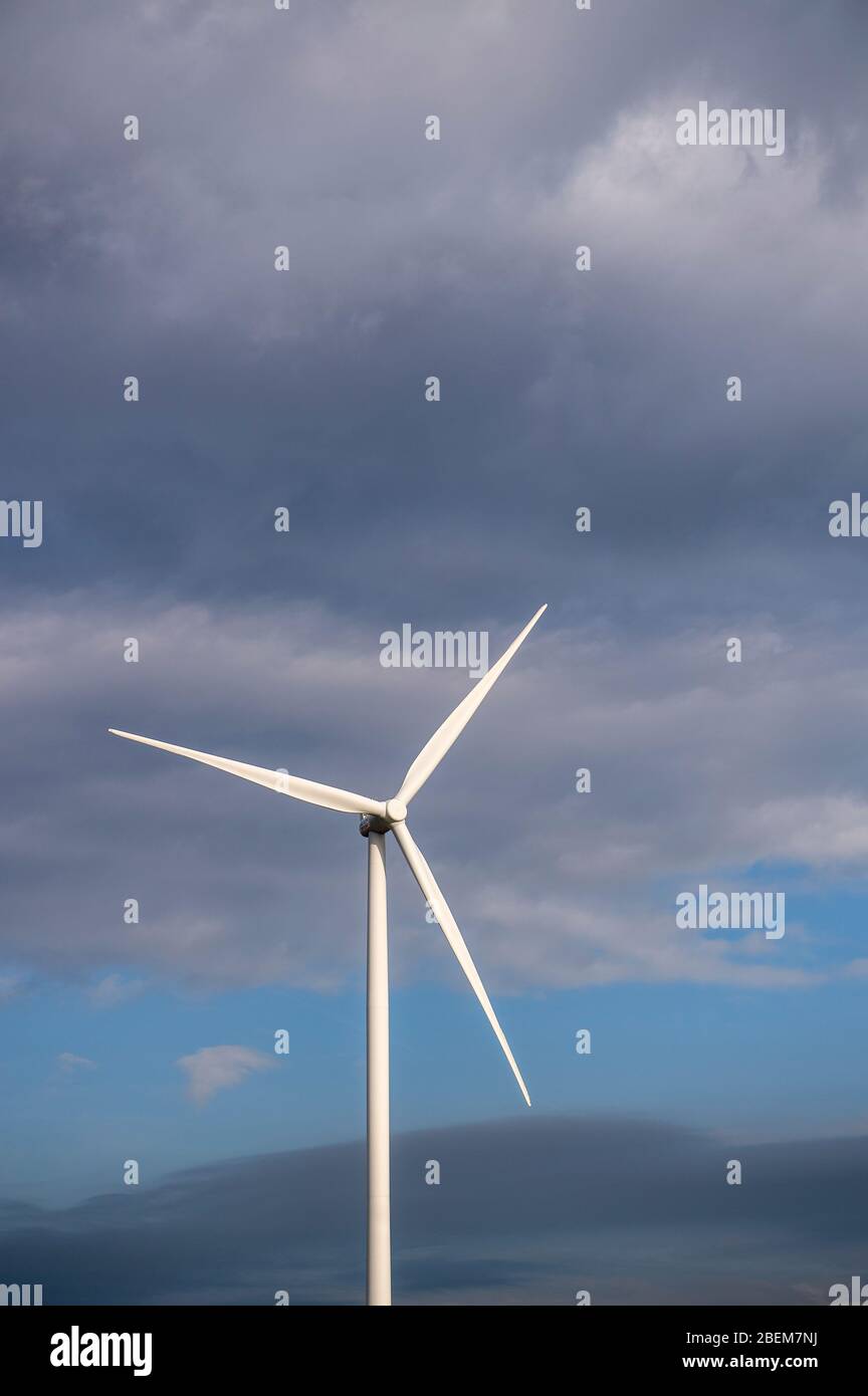 Turbina eolica singola contro un cielo nuvoloso Foto Stock