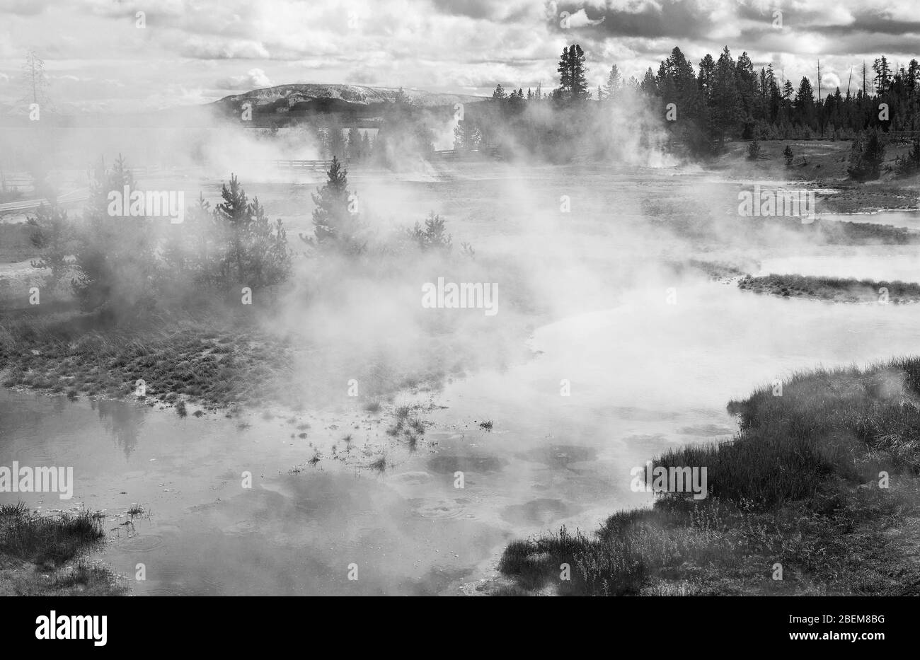 Il vapore sorge da geyser famosi in tutto il mondo nel punto di ritrovo vulcanico del Parco Nazionale di Yellowstone, Wyoming. Bianco e nero. Foto Stock