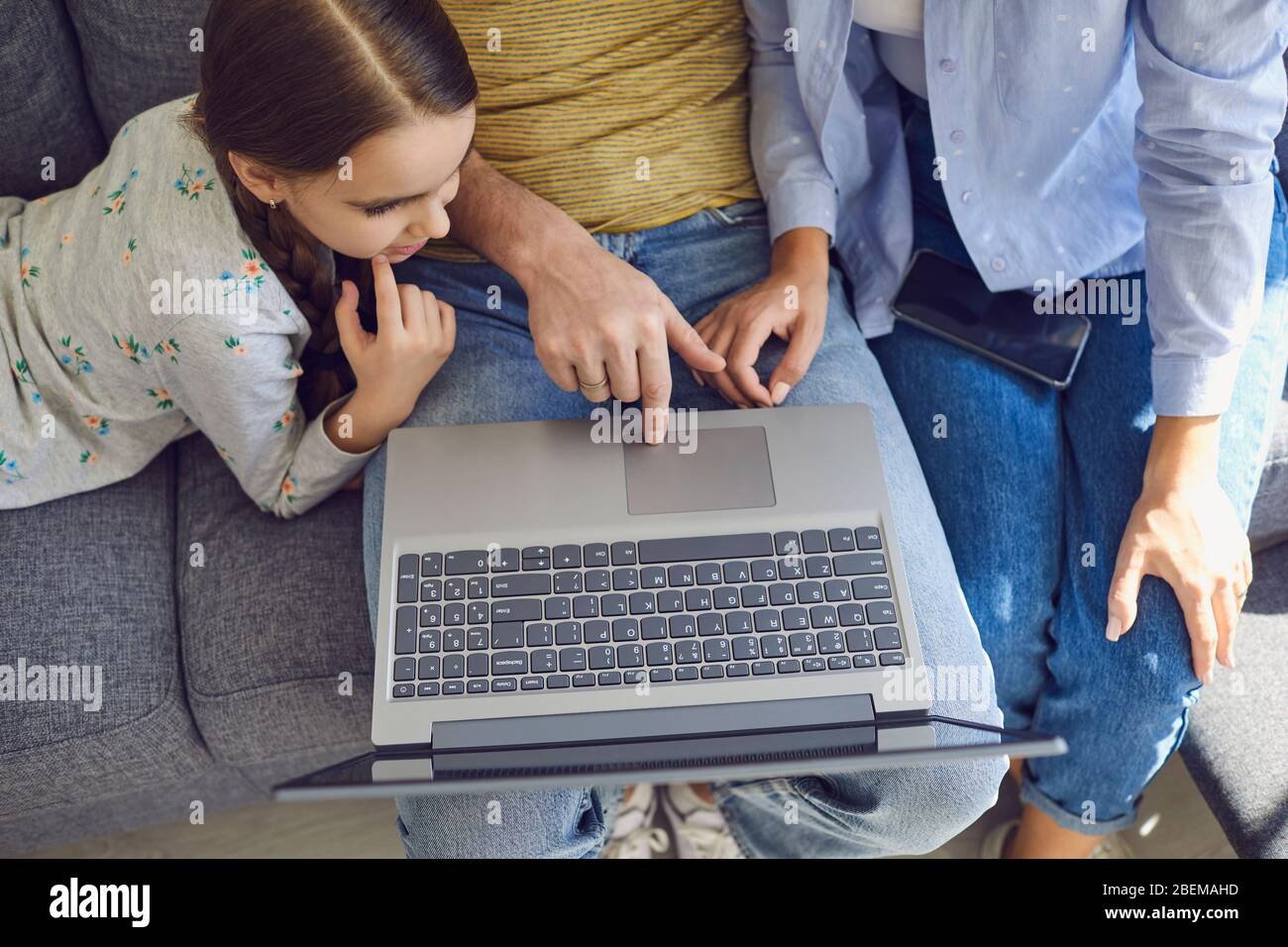 Vista dall'alto ravvicinata di una famiglia felice che utilizza il notebook mentre si è seduti a casa. Foto Stock