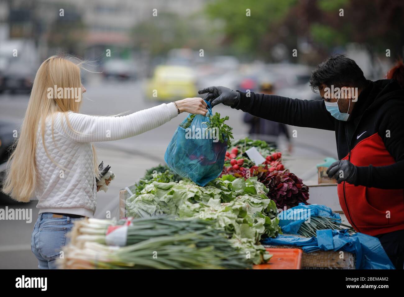 Bucarest, Romania - 14 aprile 2020: Giovane donna bionda acquista verdure da una bancarella di verdure, durante il clockdown del covid-19. Foto Stock