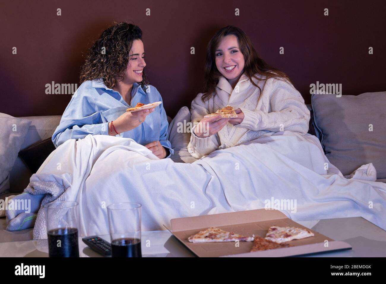 Due ragazze belle giovani che guardano la TV e si godono a casa loro Foto Stock