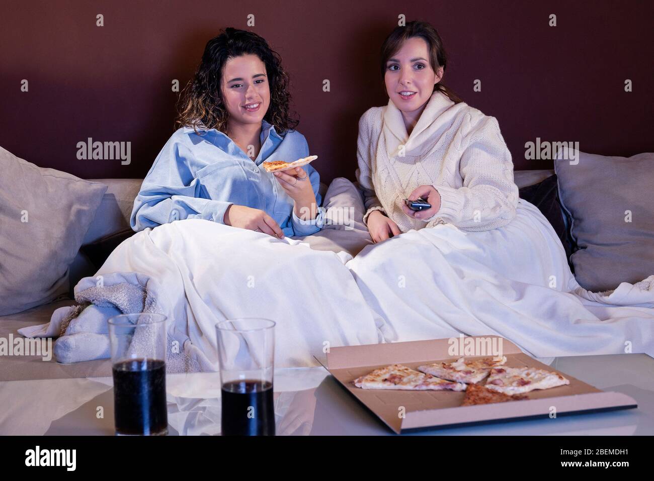 Due ragazze belle giovani che guardano la TV e si godono a casa loro Foto Stock