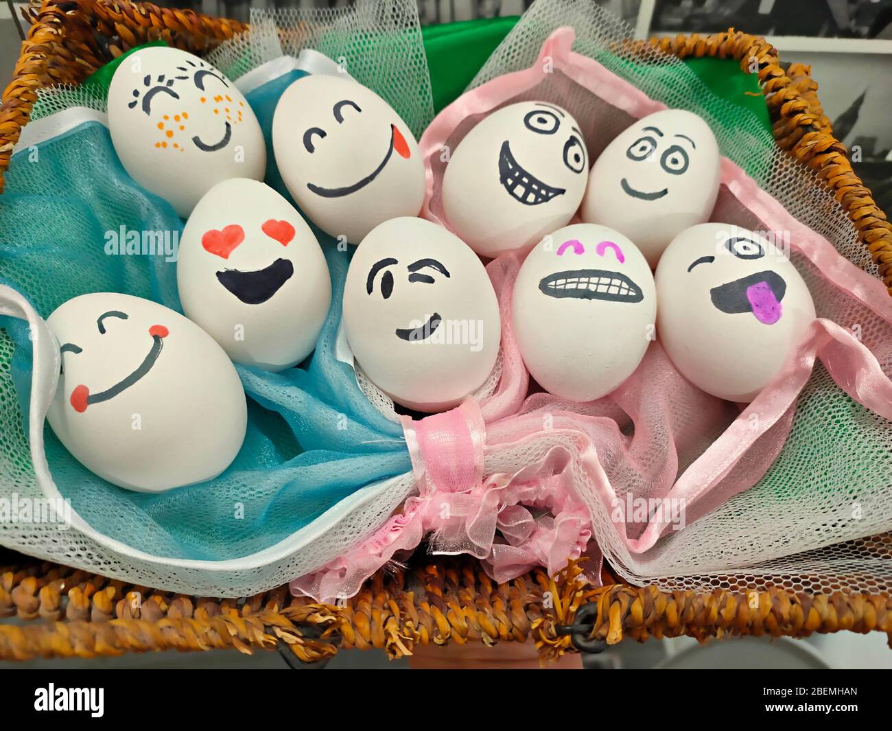 Uova di Pasqua in un cesto con facce e cuori dipinti invece degli occhi Foto Stock