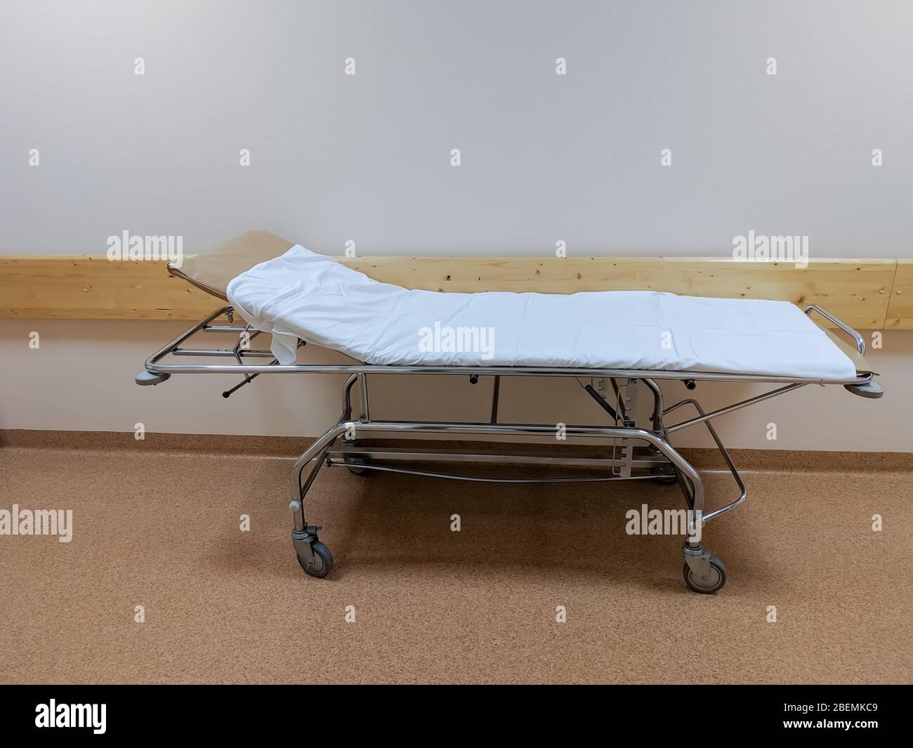 Un letto di gurney coperto da un foglio bianco o una barella su ruote per il trasporto di pazienti bedridden nel corridoio dell'ospedale Foto Stock