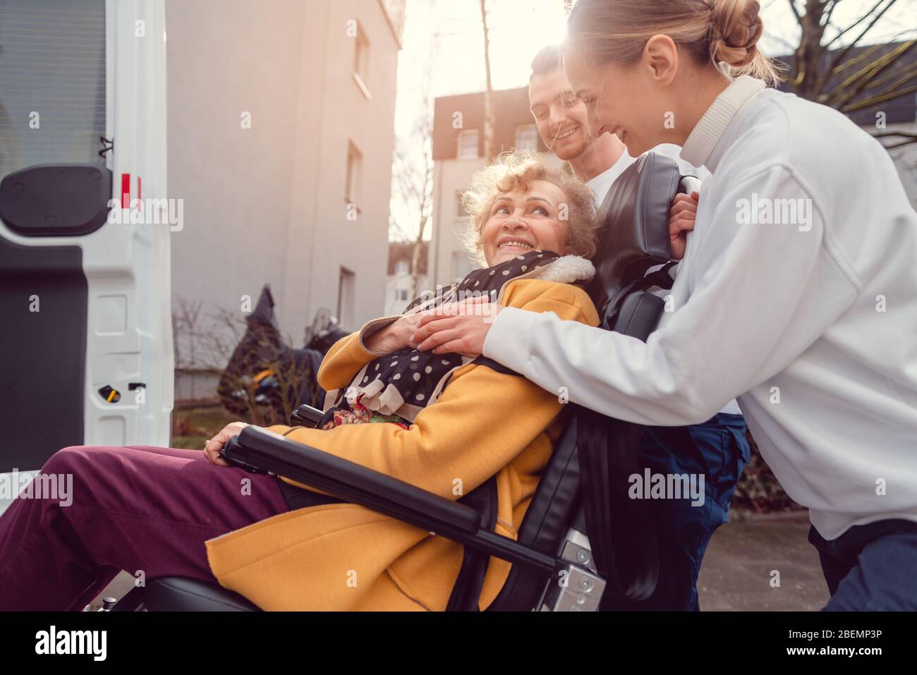 Donna anziana in sedia a rotelle che viene ritirata dal servizio di trasporto Foto Stock