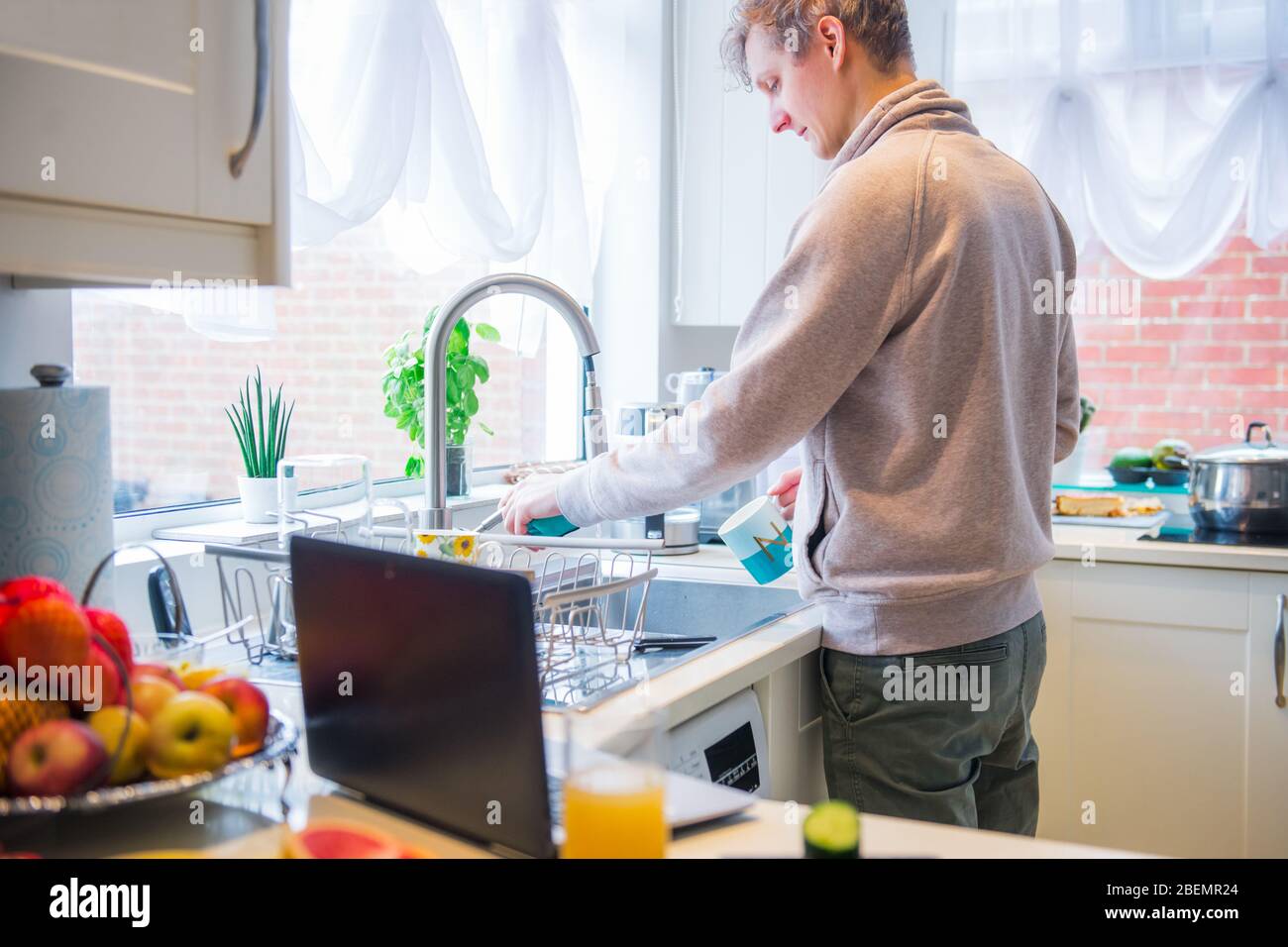 Uomo che usa il computer portatile e cucina in cucina a casa. Acquisto di  generi alimentari online. Pagina web del negozio online di alimenti sullo  schermo verdure fresche in cucina Foto stock -