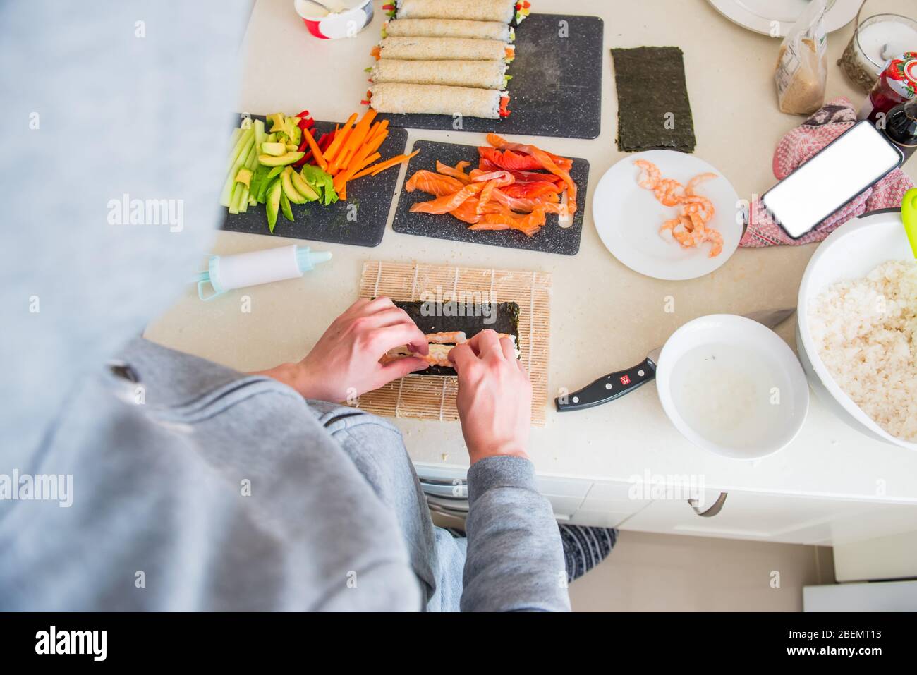 Top vedere le mani maschili fare sushi a casa dopo aver cucinato online video classi sul sito web via smartphone. Tecnologia Internet per lo stile di vita moderno co Foto Stock