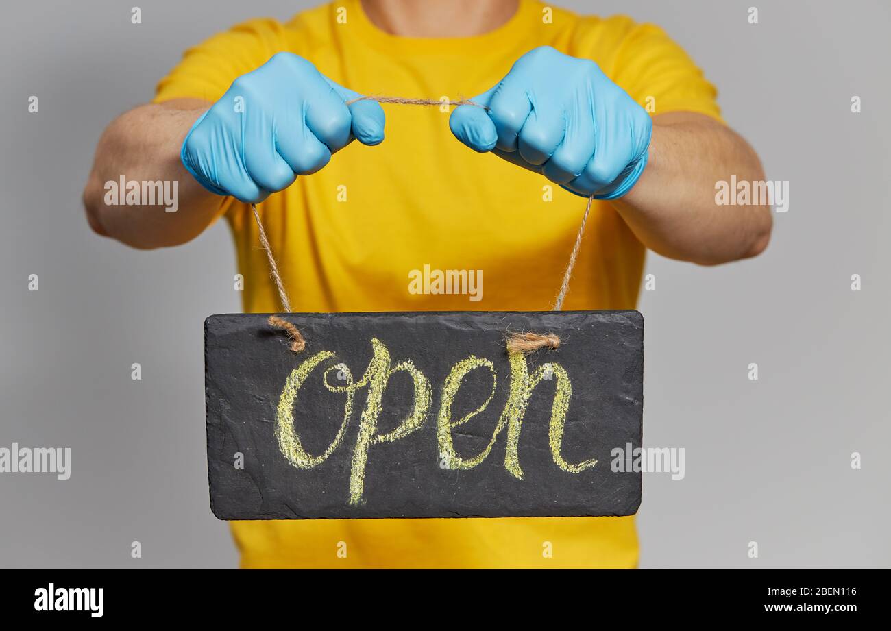 Cavetto in uniforme gialla, maschera protettiva e guanti con il testo Apri. Servizio di consegna Foto Stock