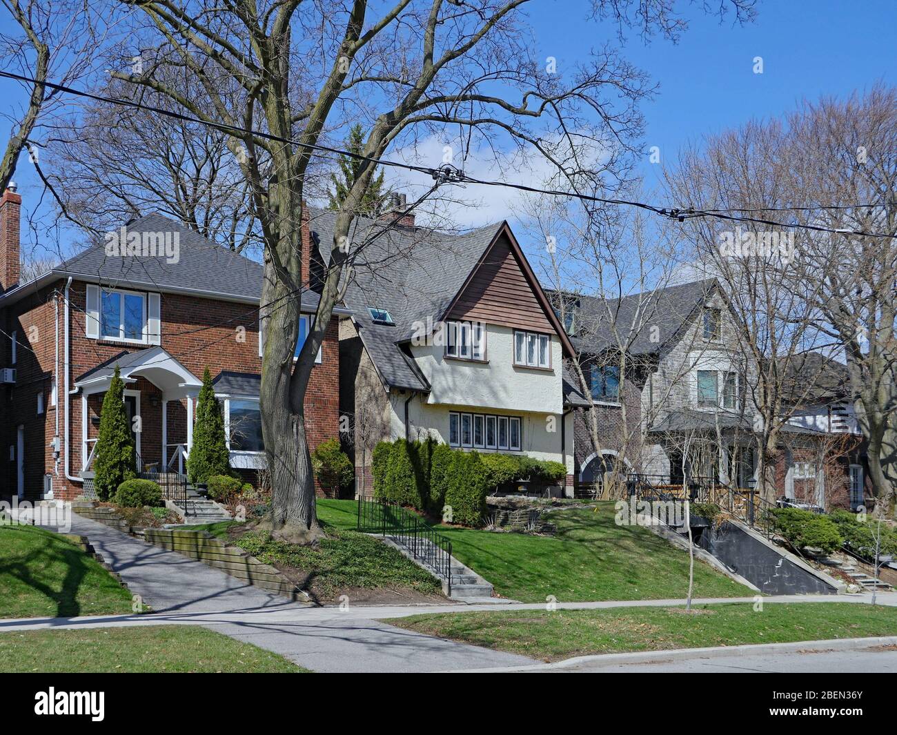 Strada residenziale con grandi case indipendenti con cortili di fronte e alberi maturi Foto Stock