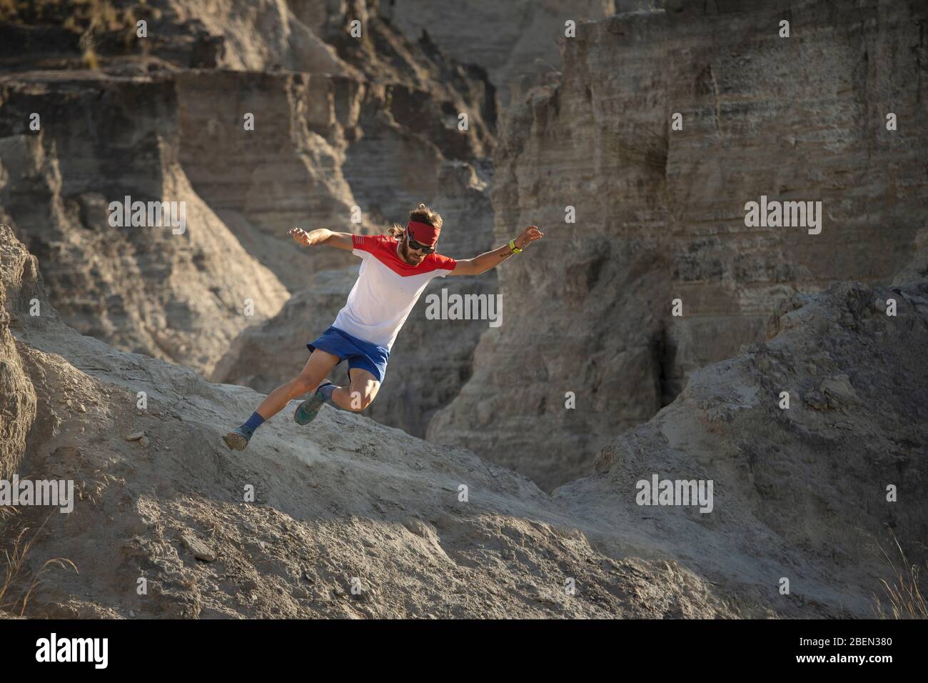 Un uomo che corre veloce su terreno sabbioso e arido Foto Stock