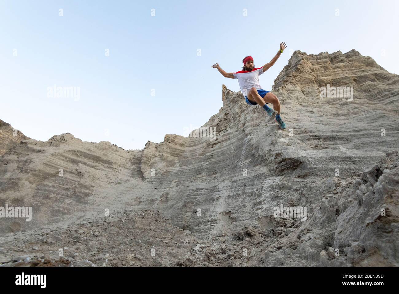 Un uomo corre giù su un muro molto ripido ad un vecchio spreco minerario di sabbia Foto Stock