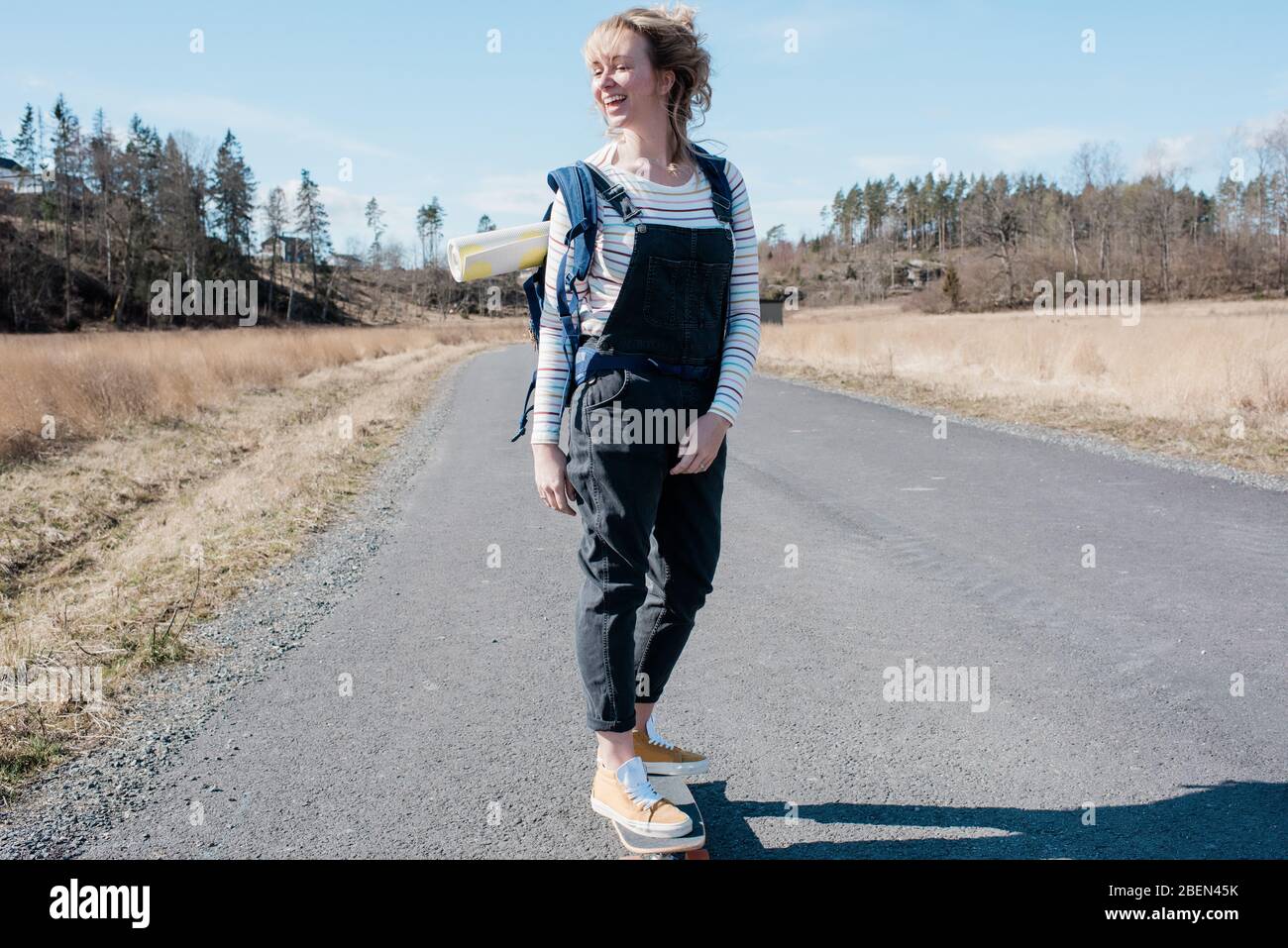 donna che ama pattinare lungo una strada di campagna dalla lezione di yoga Foto Stock