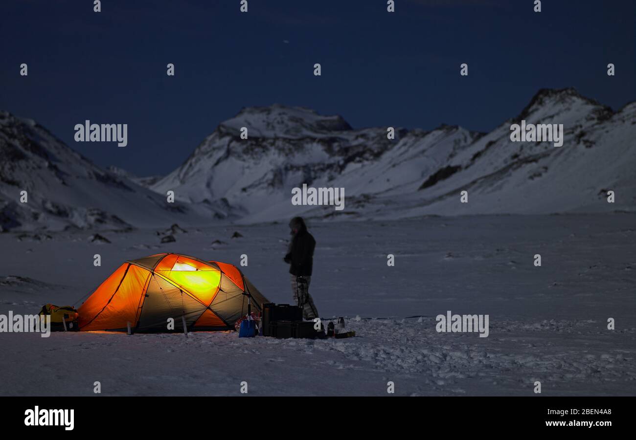 Tenda illuminata al campo nel paesaggio invernale islandese Foto Stock