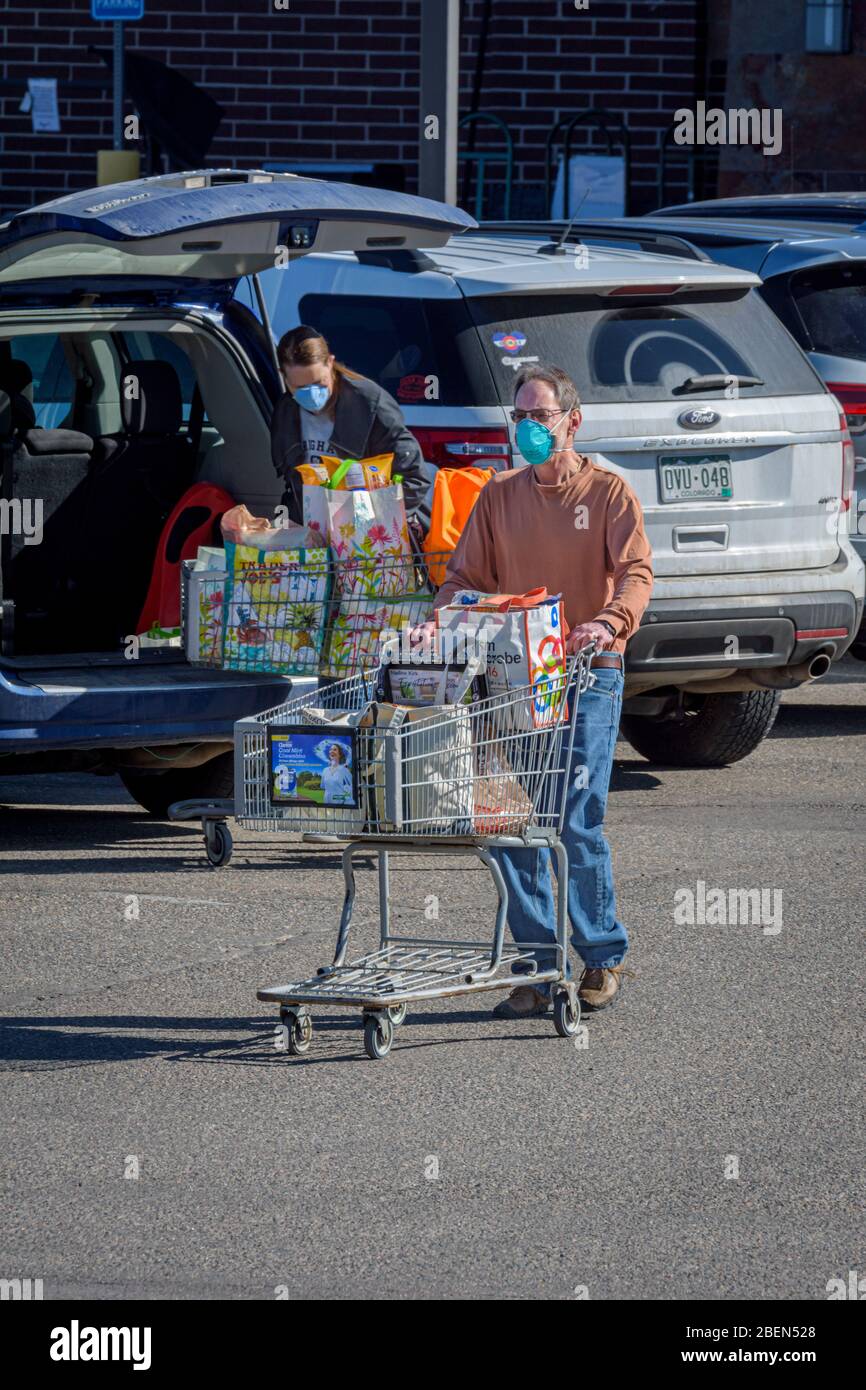 I clienti di alimentari che indossano maschere facciali protettive a causa dei generi alimentari di trasporto del virus Corona Covid-19 alle loro auto, Castle Rock Colorado USA. Foto Stock
