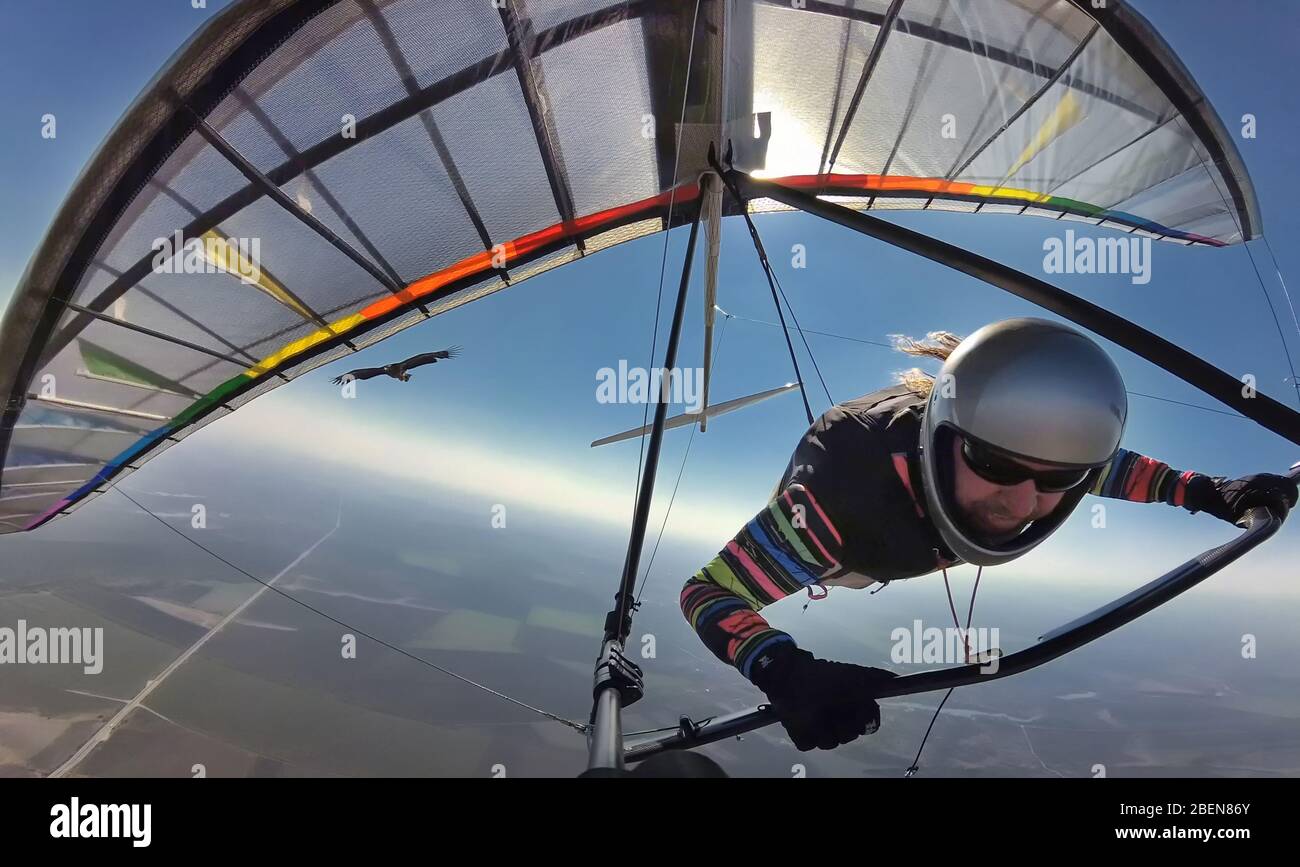 Il pilota di deltaplano sulle ali colorate vola insieme all'aquila. Sogno di volare come un uccello diventare realtà. Distanza sociale nella natura selvaggia lontano da altro Foto Stock
