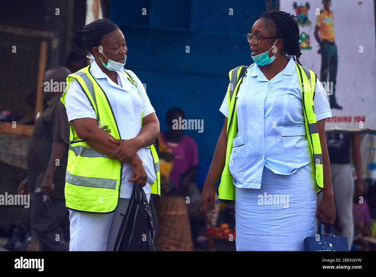 Due operatori del servizio medico chiacchierano mentre aspettano il trasporto ad una fermata di autobus a Lagos, Nigeria. Foto Stock