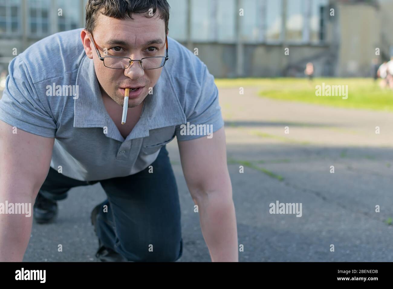 un passerby con una sigaretta si trova allo stadio nel supporto di partenza per una corsa sul tapis roulant Foto Stock