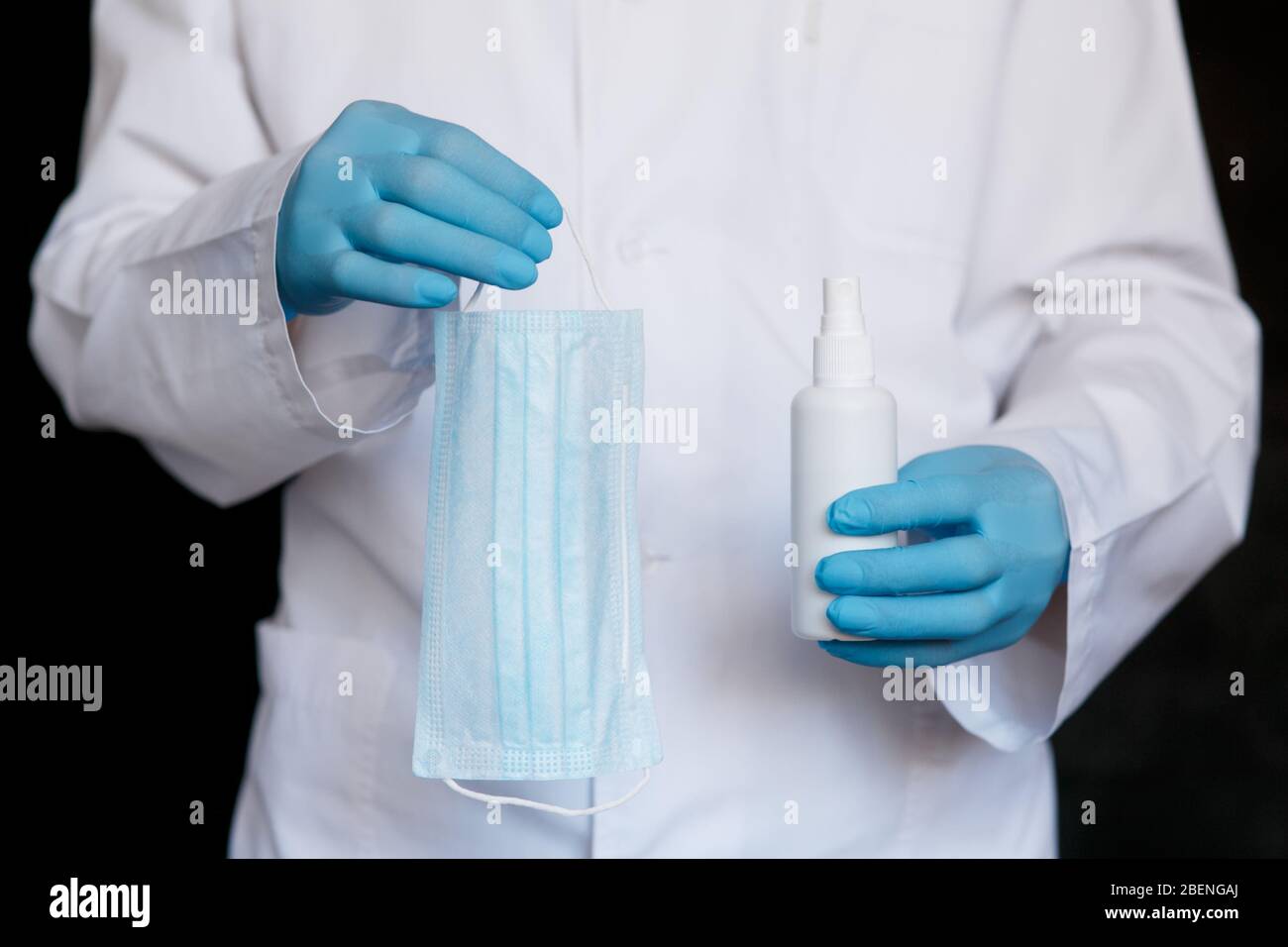 Spray gel antisettico per soluzione alcolica, maschera facciale medica, set igienico per il controllo del coronavirus su sfondo grigio, primo piano Foto Stock
