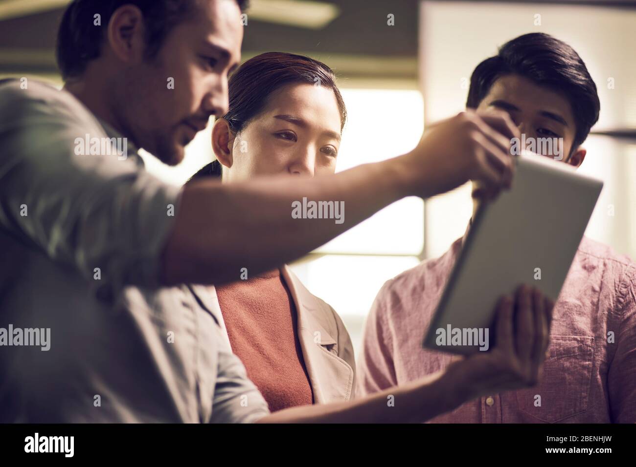 tre giovani imprenditori asiatici che lavorano insieme in ufficio guardando il tablet digitale Foto Stock