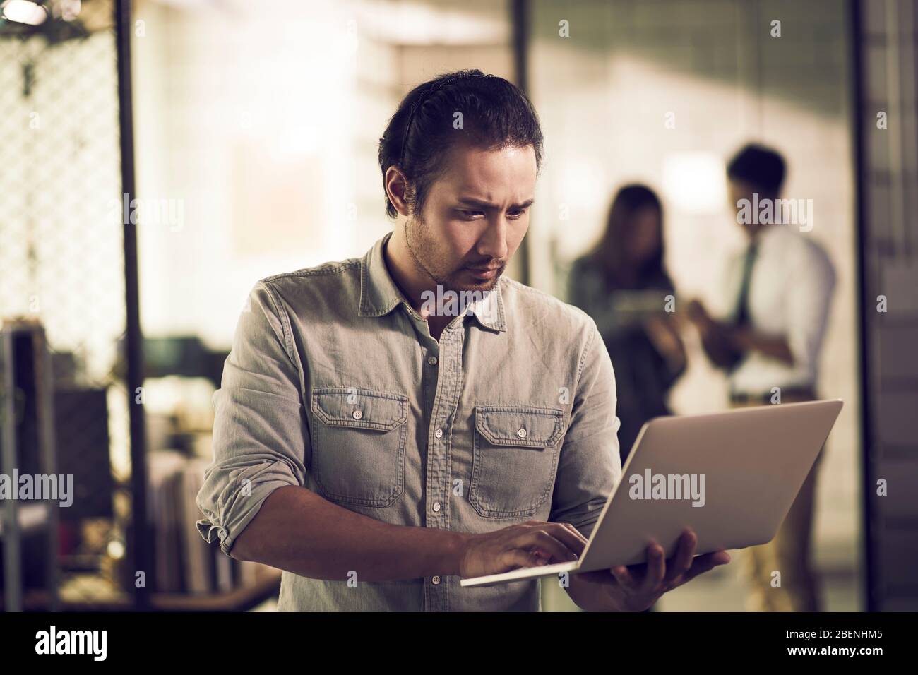 giovane imprenditore asiatico che controlla informazioni o dati utilizzando computer portatile in ufficio Foto Stock